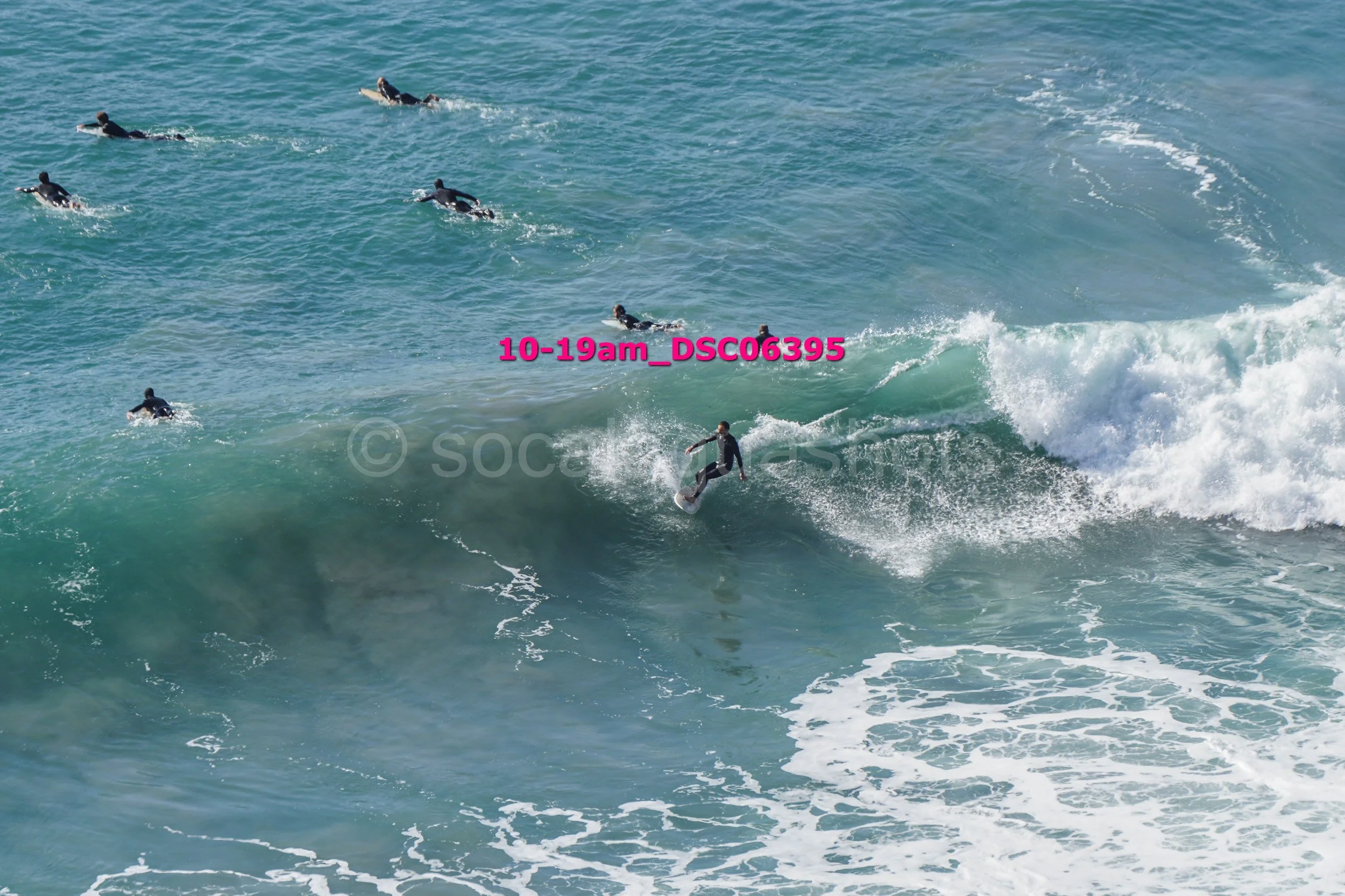 Surfer riding a wave with several surfers in the water watching nearby