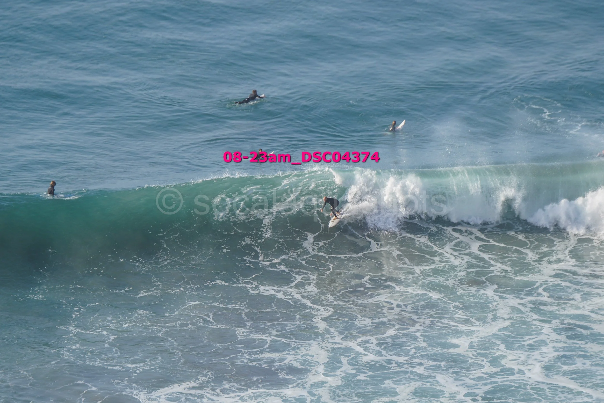 Surfer riding a wave with several surfers in the distance in the ocean.