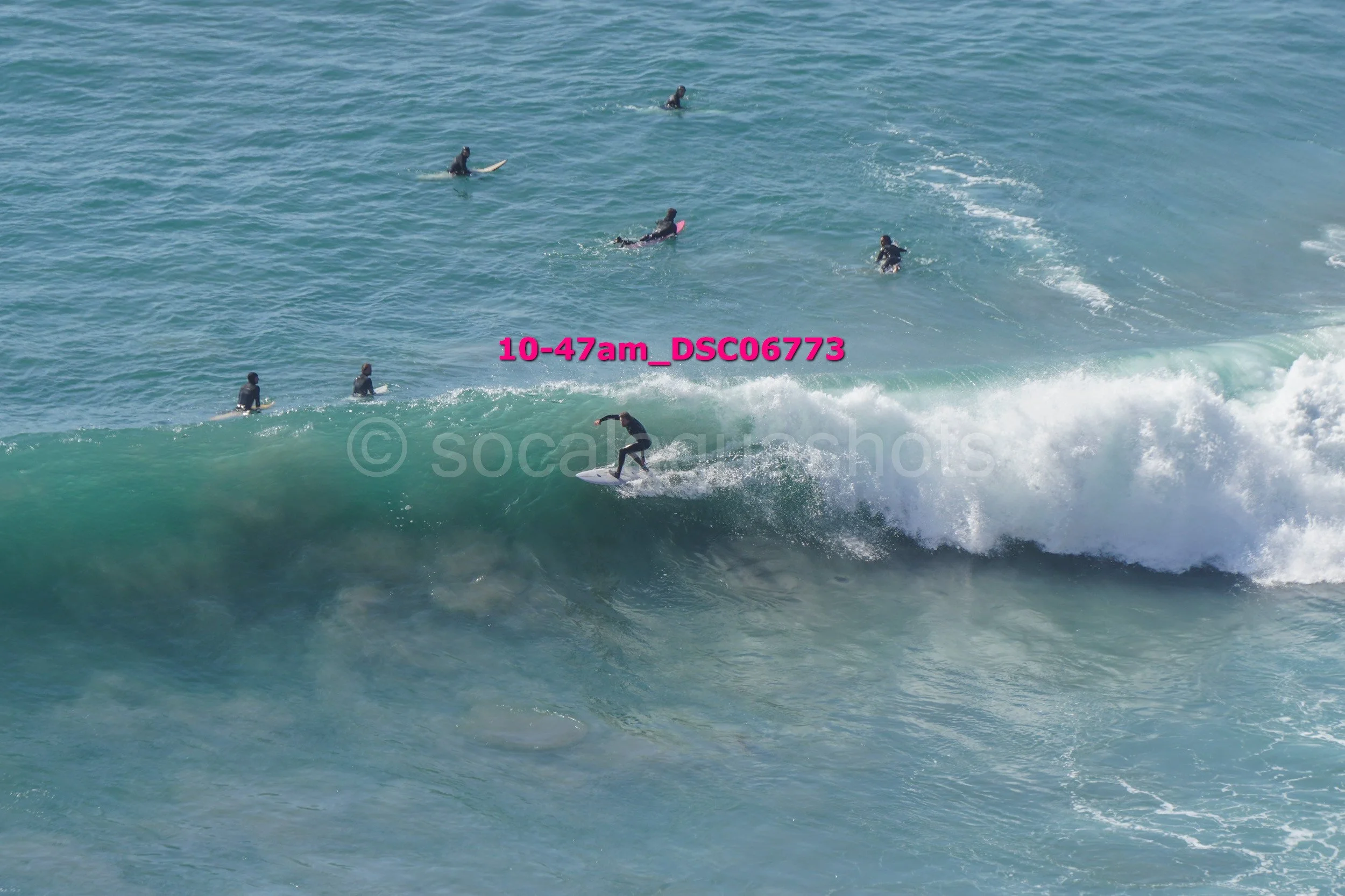 Surfer riding a wave with several people in the water watching or waiting in the distance