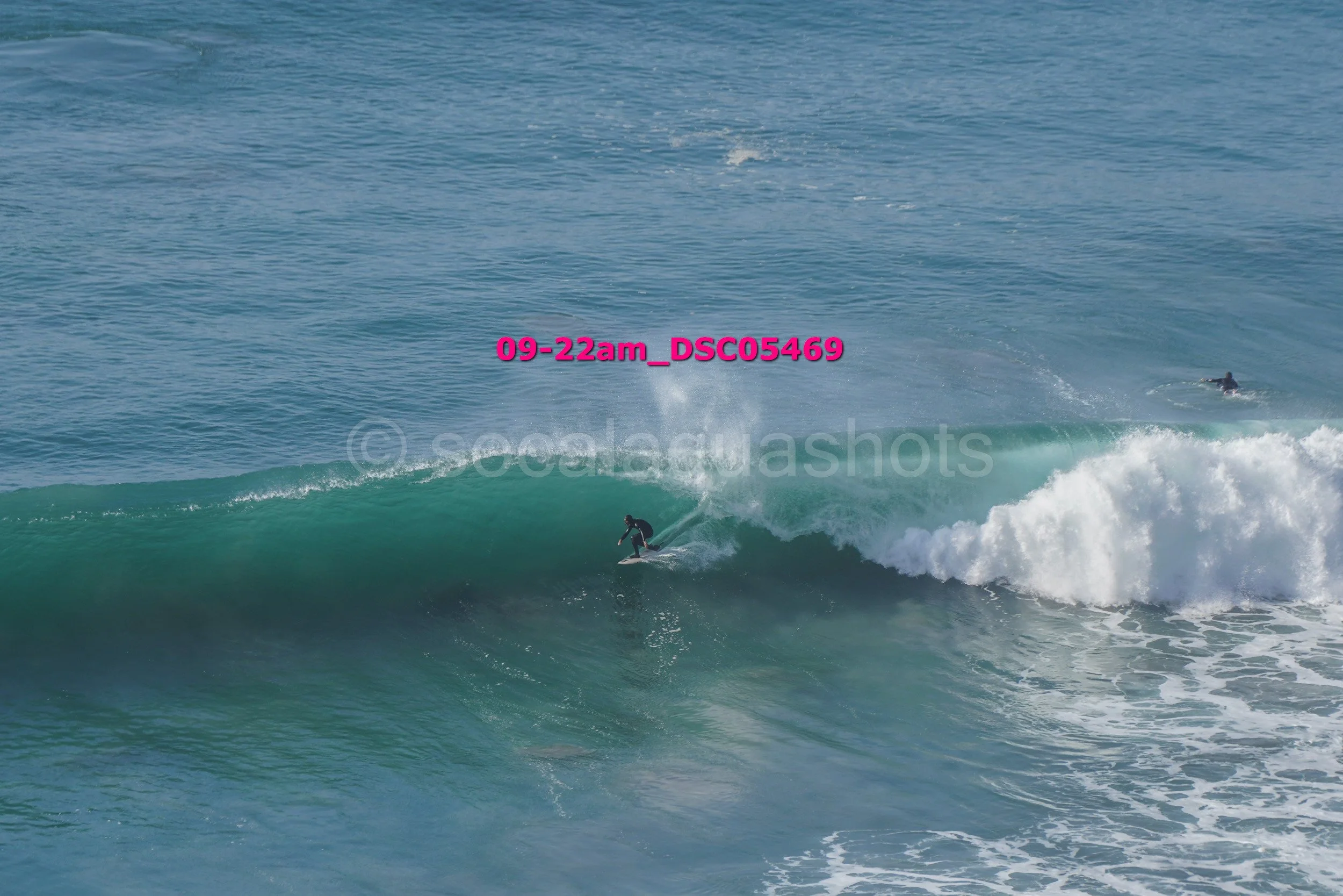 A person surfing a wave in the ocean with two other people in the background.