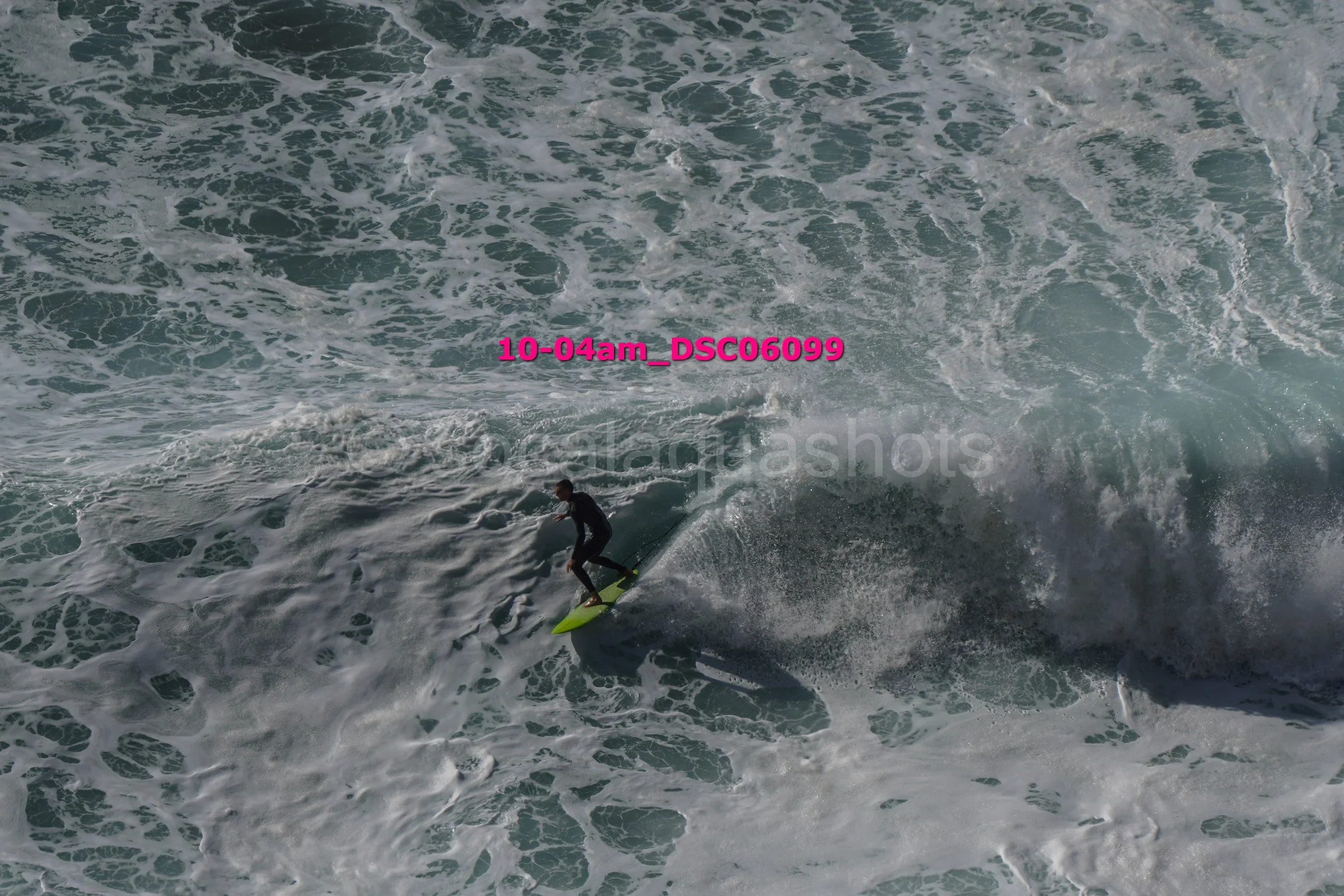A person surfing on a large wave in the ocean with frothy white water, wearing a wetsuit and riding a yellow surfboard.
