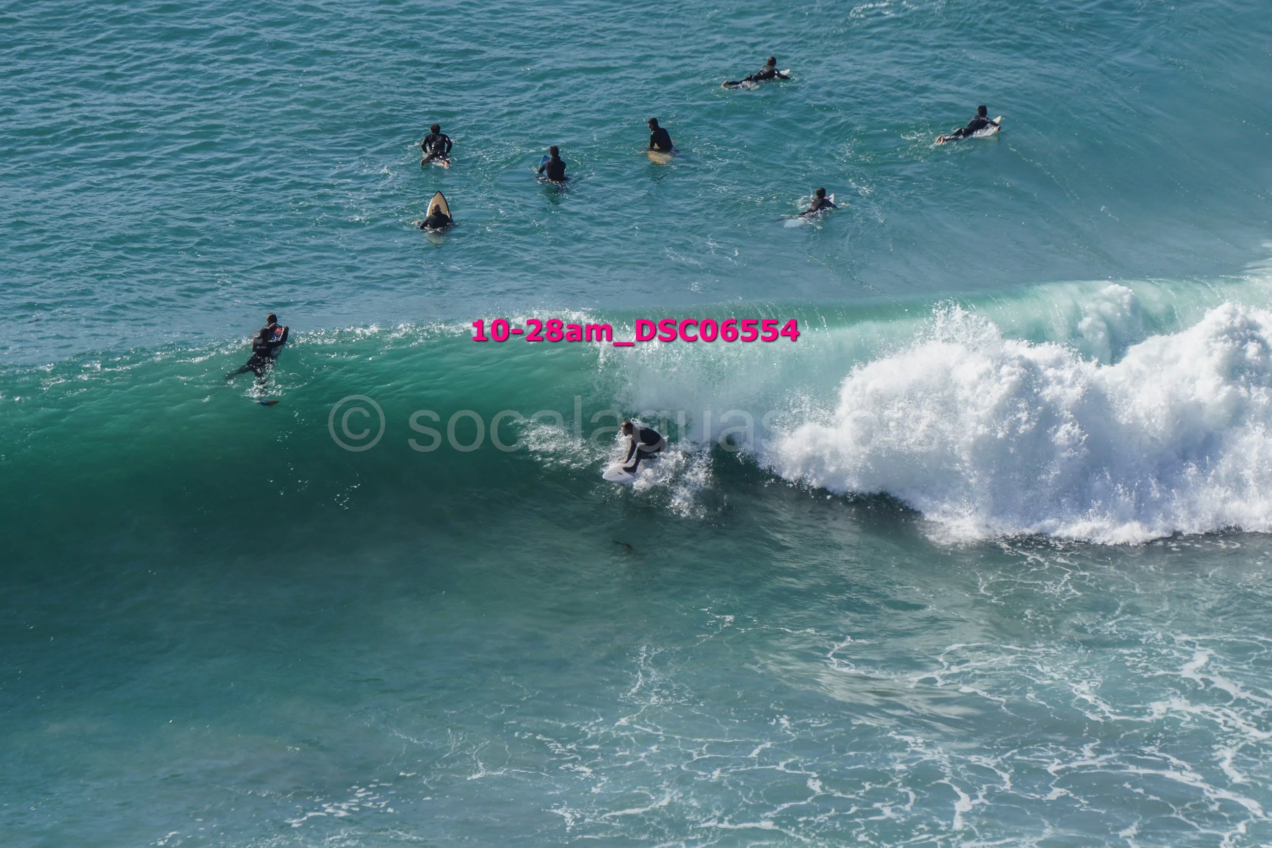 Surfer riding a wave with several surfers in the ocean in the background.