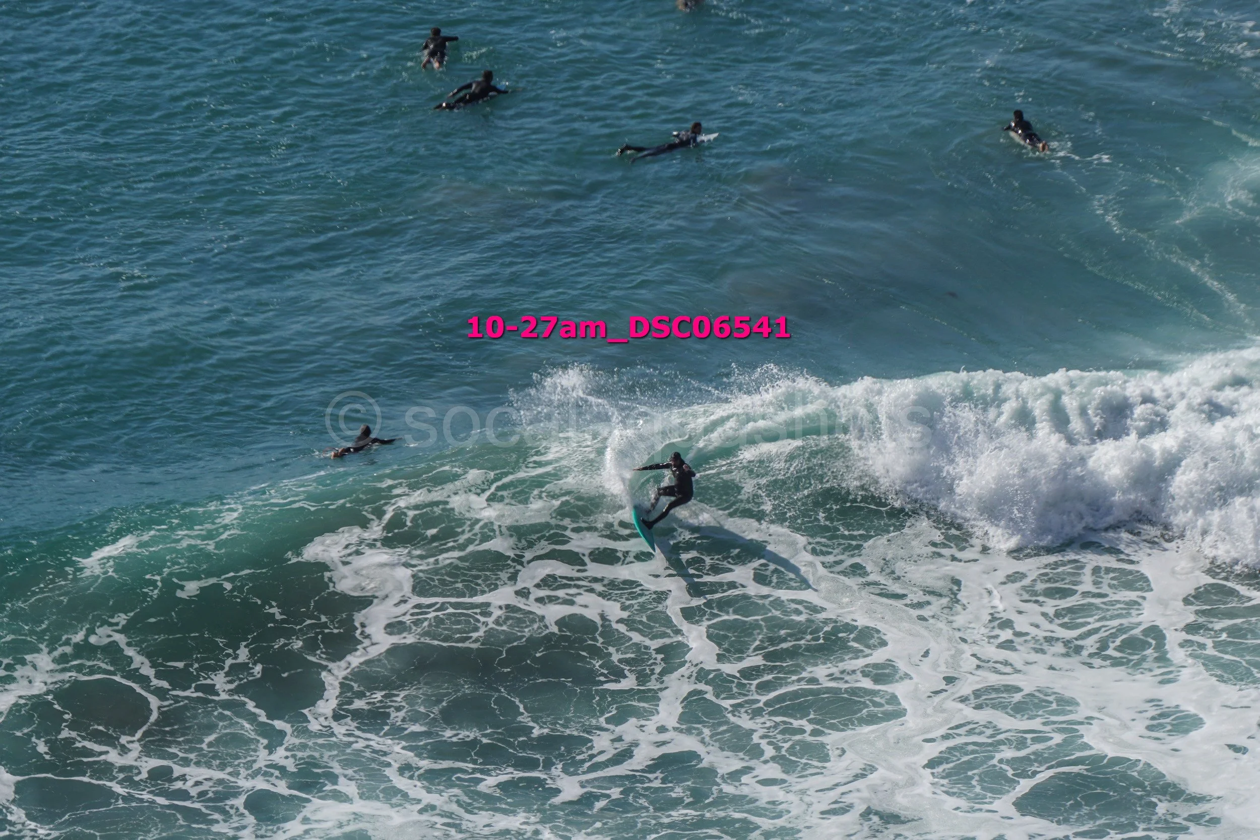 Surfer riding a wave with several other surfers in the background