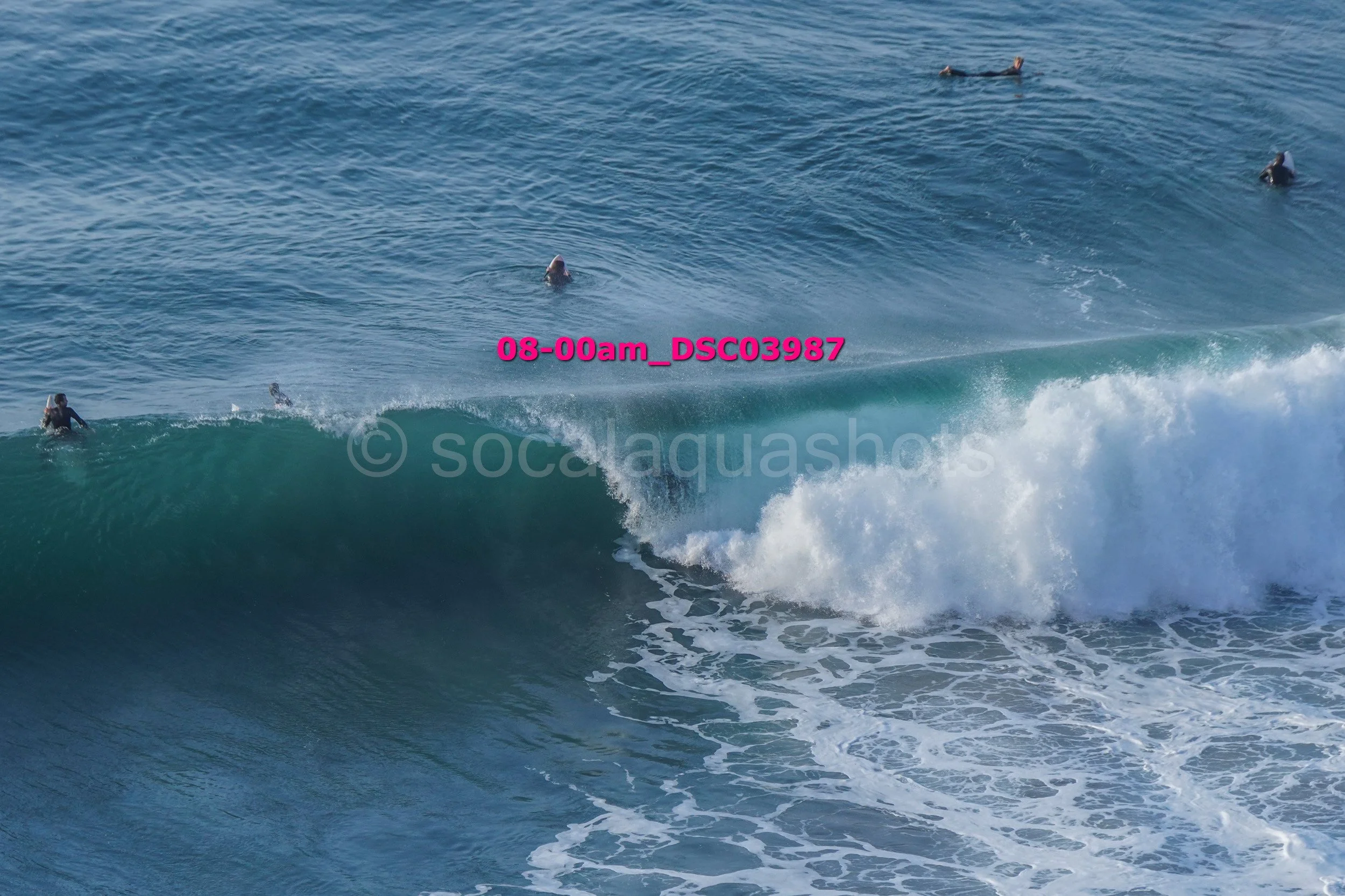 Surfers riding a wave in the ocean with some surfers in the distance.