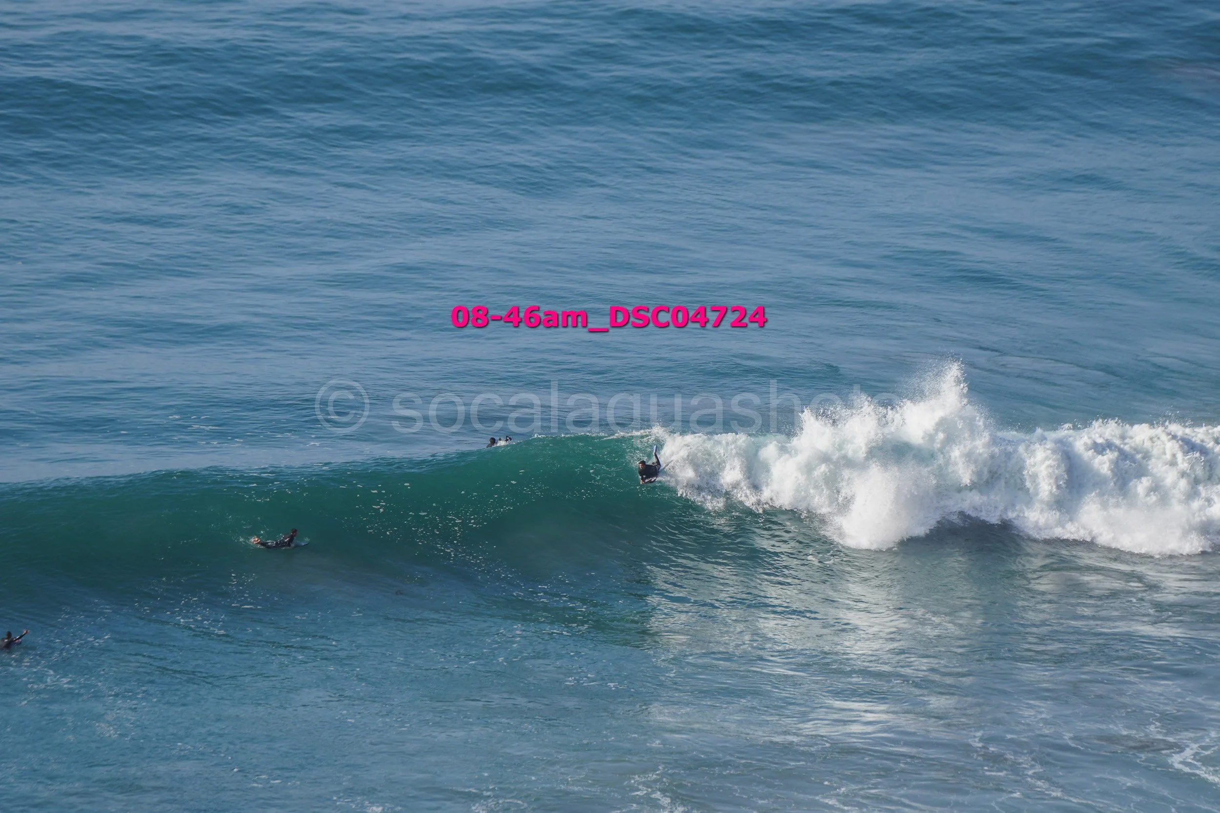 Surfers riding a wave in the ocean during daytime.