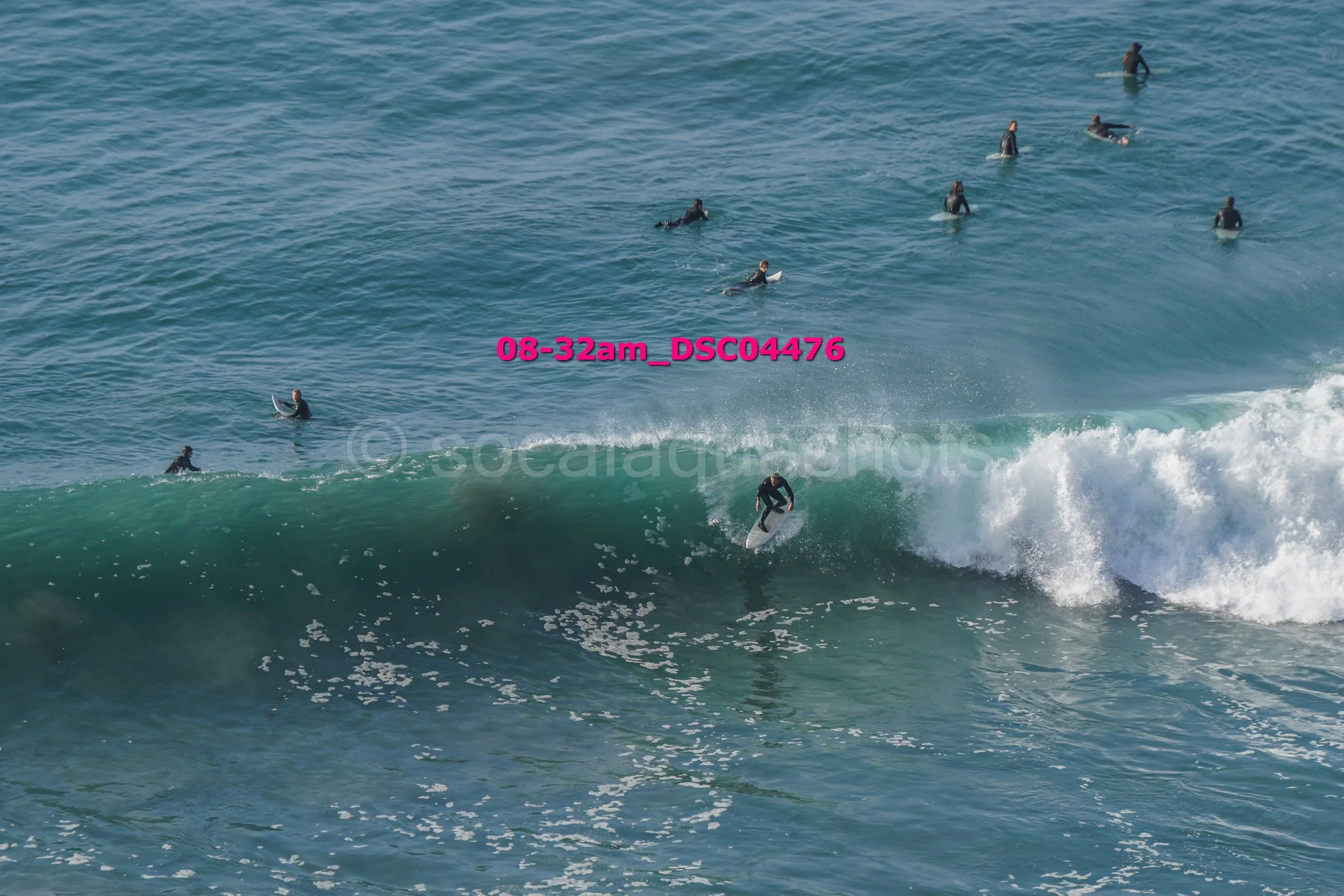 Surfer riding a wave with several surfers in the water observing.