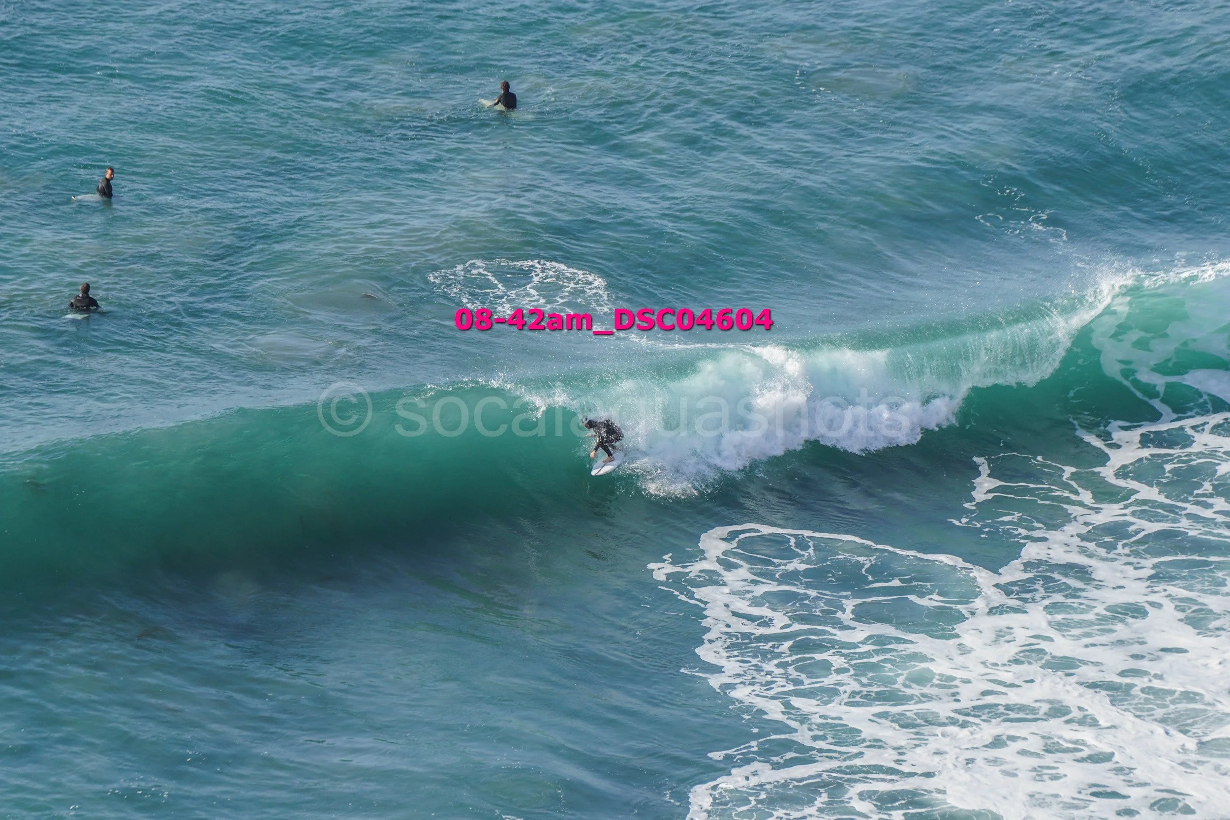 Surfer riding a wave with three surfers in the water nearby