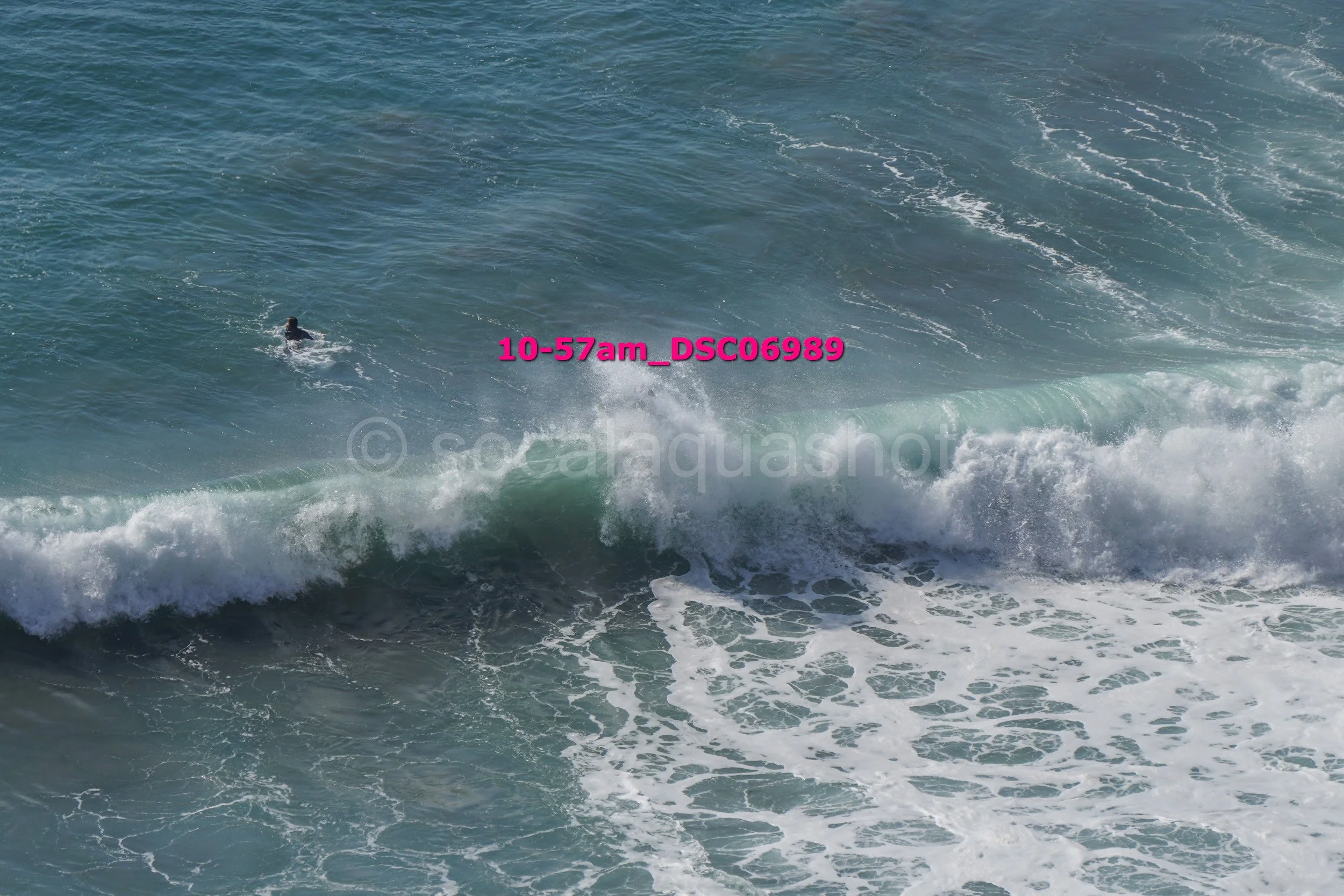 A person swimming in the ocean near a breaking wave.