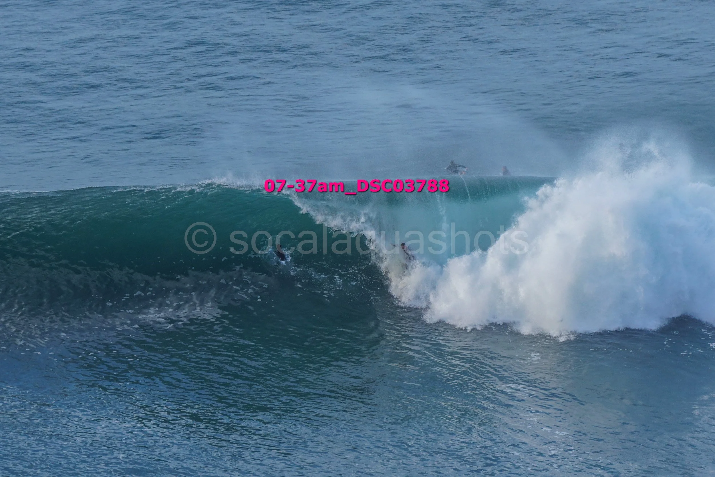 Two surfers riding a wave in the ocean, with the water crashing around them.