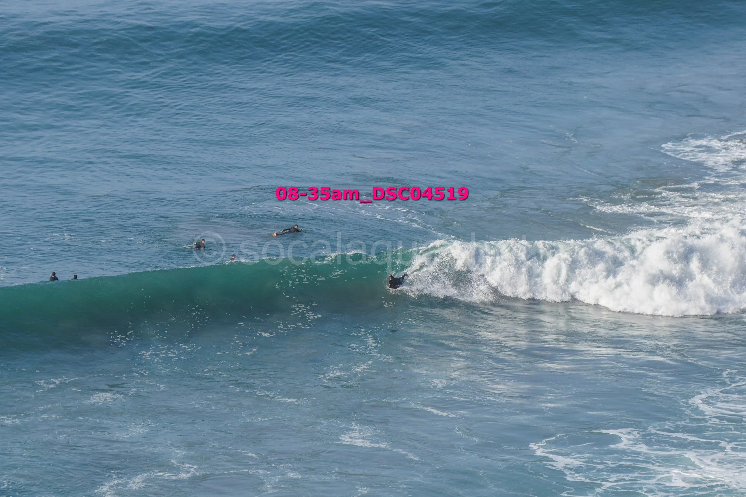People surfing on a large ocean wave during daytime.