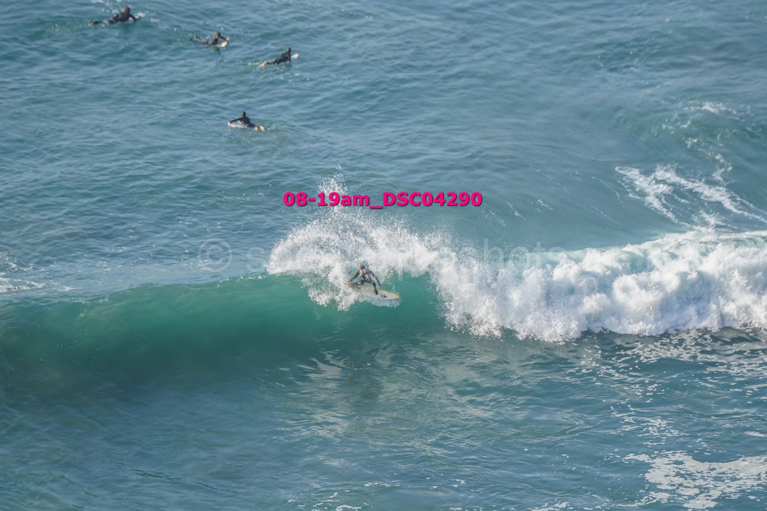 Surfer riding a wave with several surfers in the water in the background