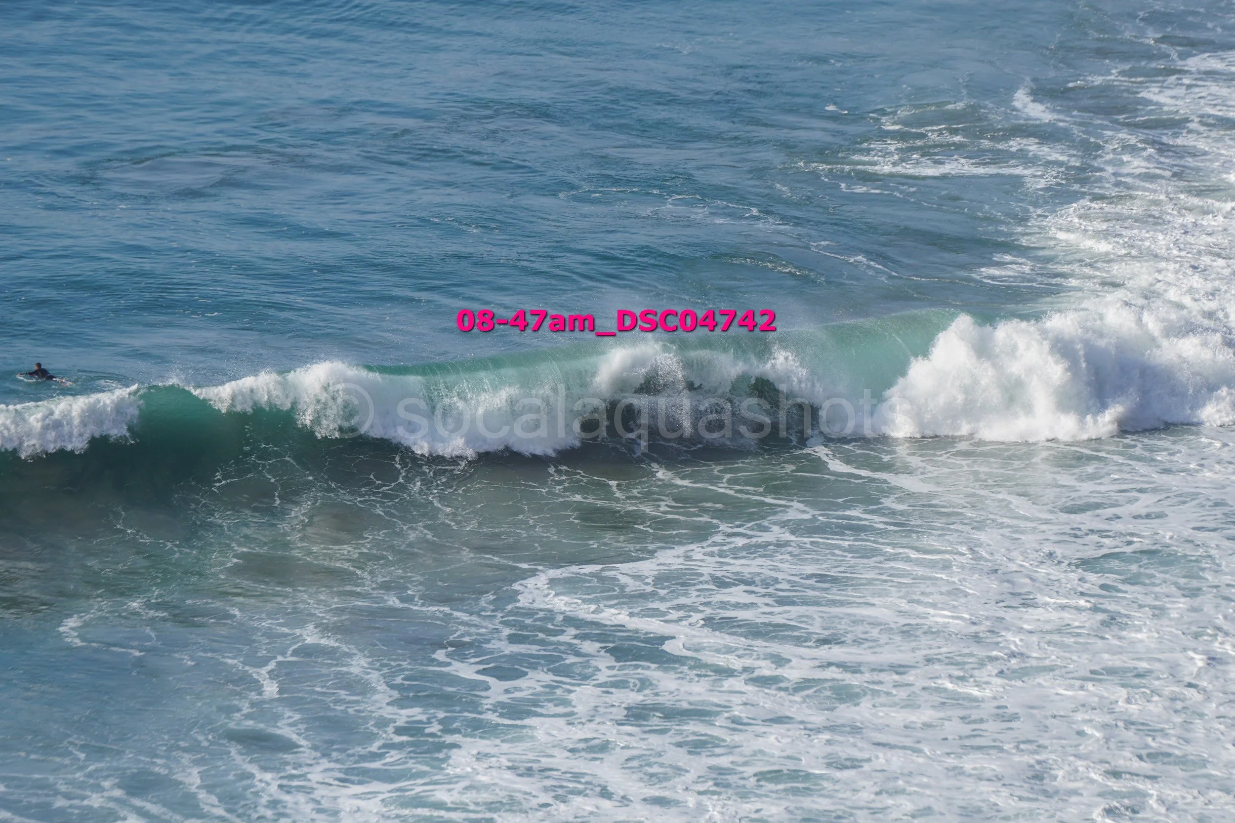 Ocean waves with a person surfing in the distance.