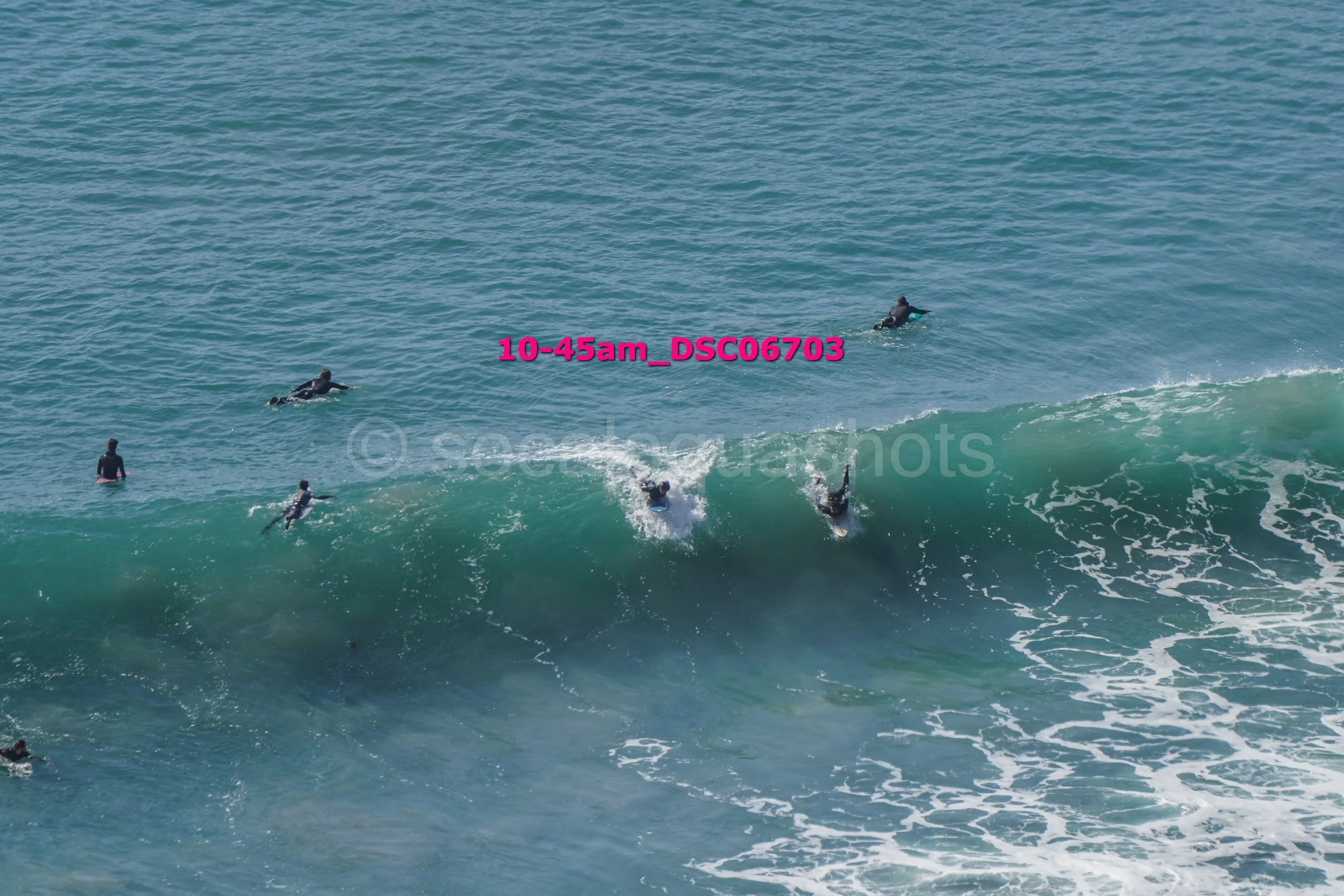 People surfing and swimming in the ocean with waves breaking.