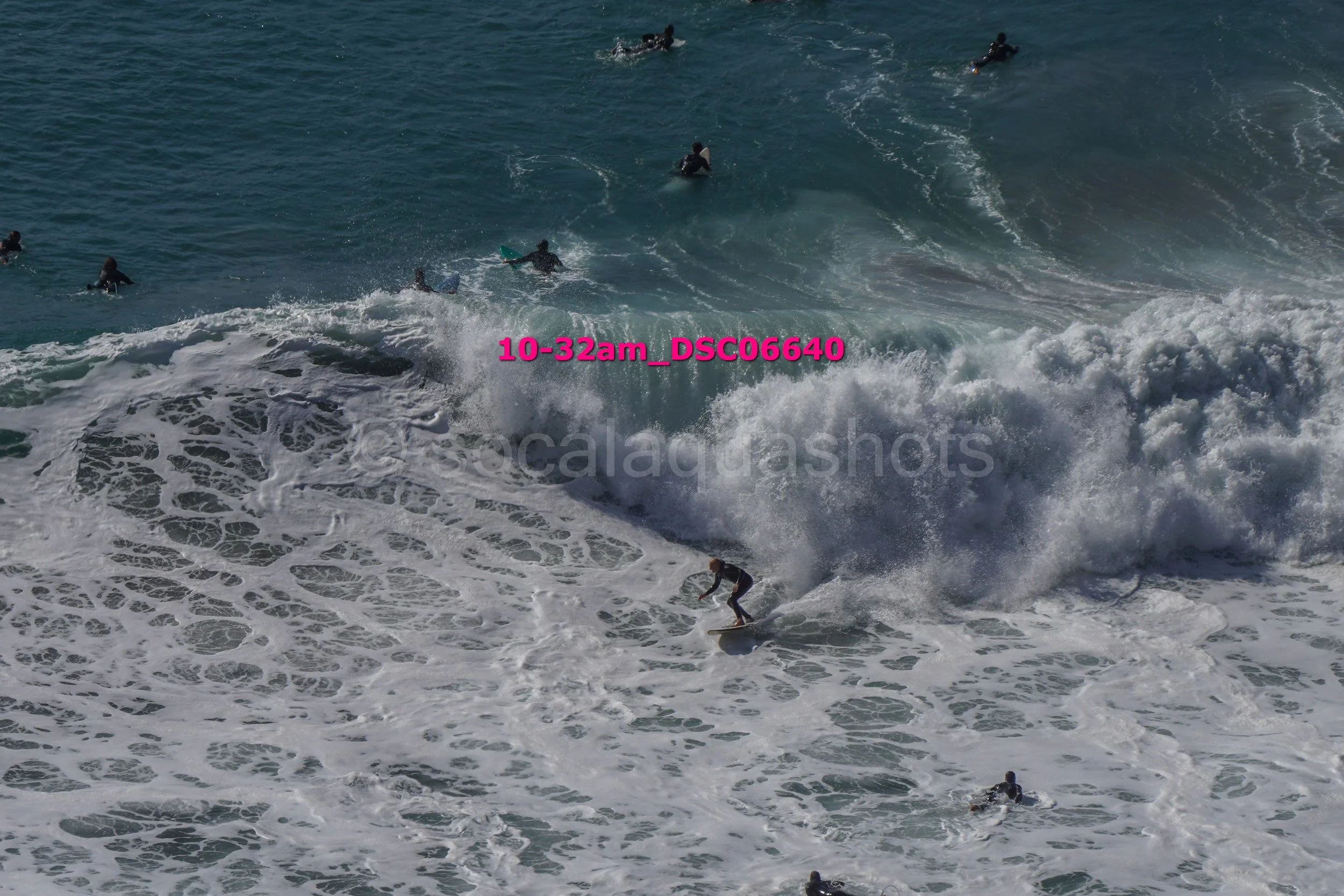 Surfer riding a wave with multiple surfers in the water.