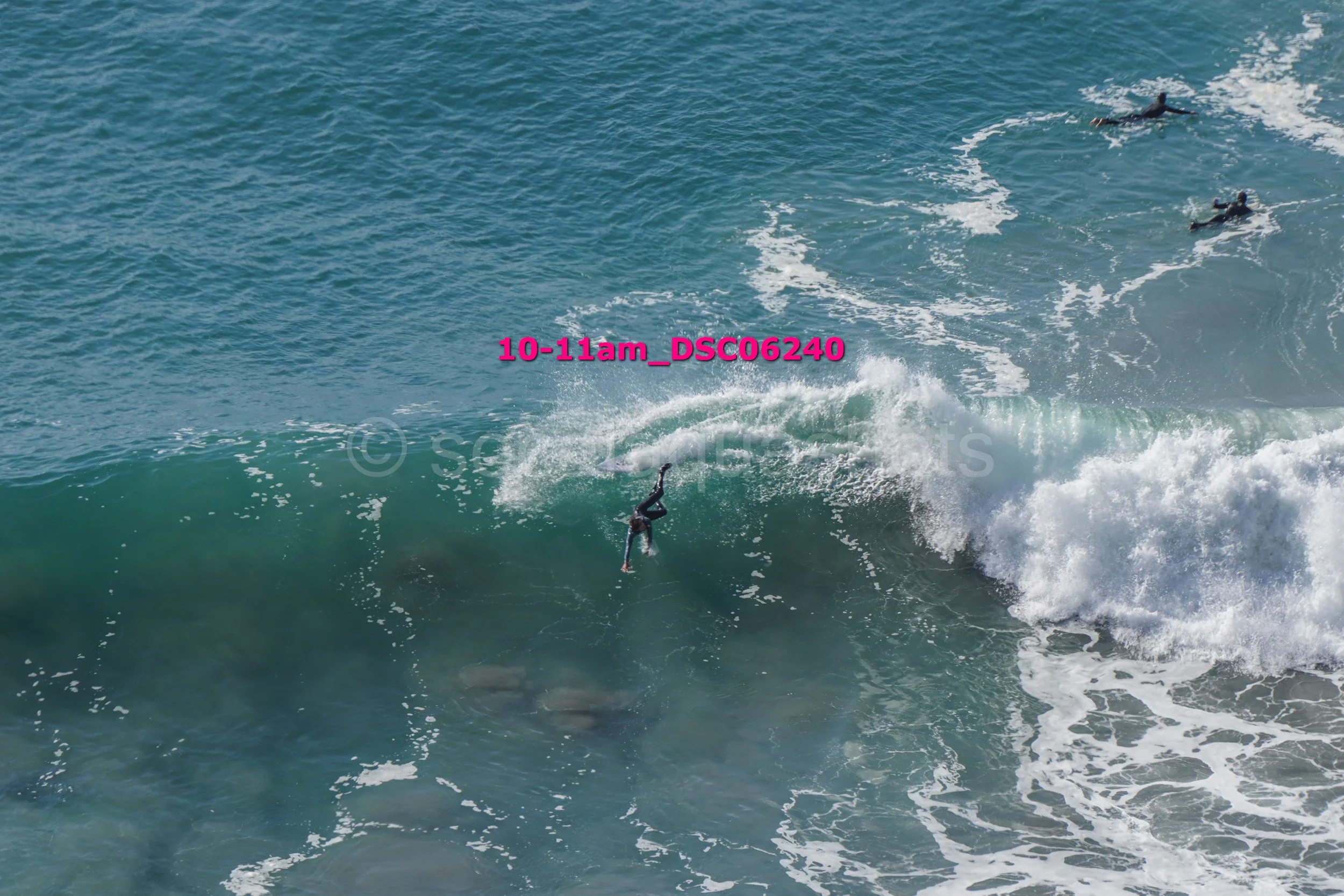 Surfer falling off her surfboard as waves crash at the beach.