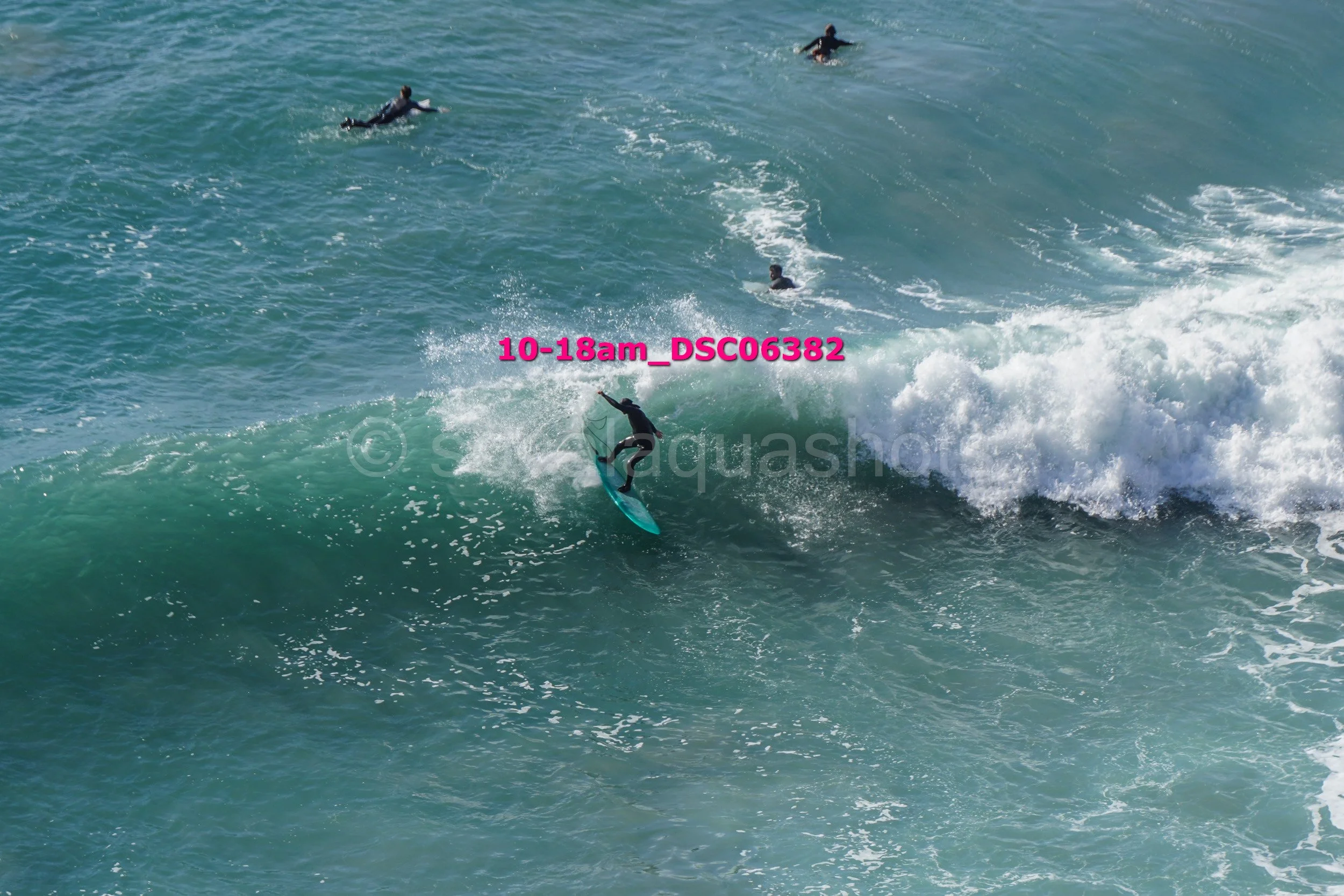 Surfer riding a wave in the ocean with several other surfers in the background.