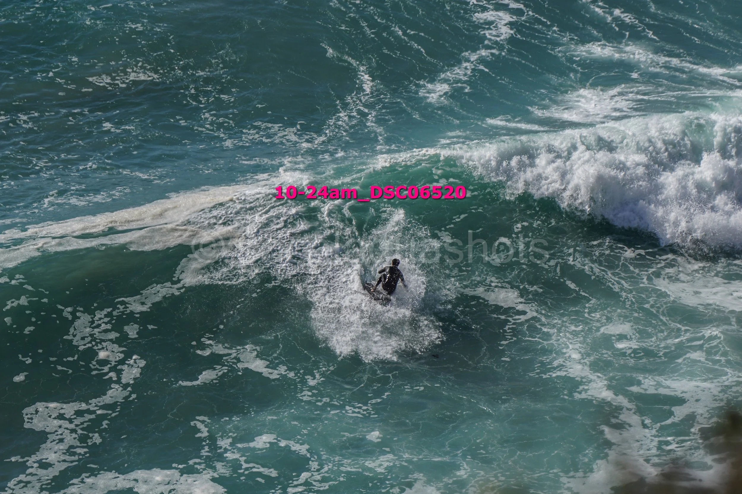 A person on a surfboard riding a large ocean wave during daytime.