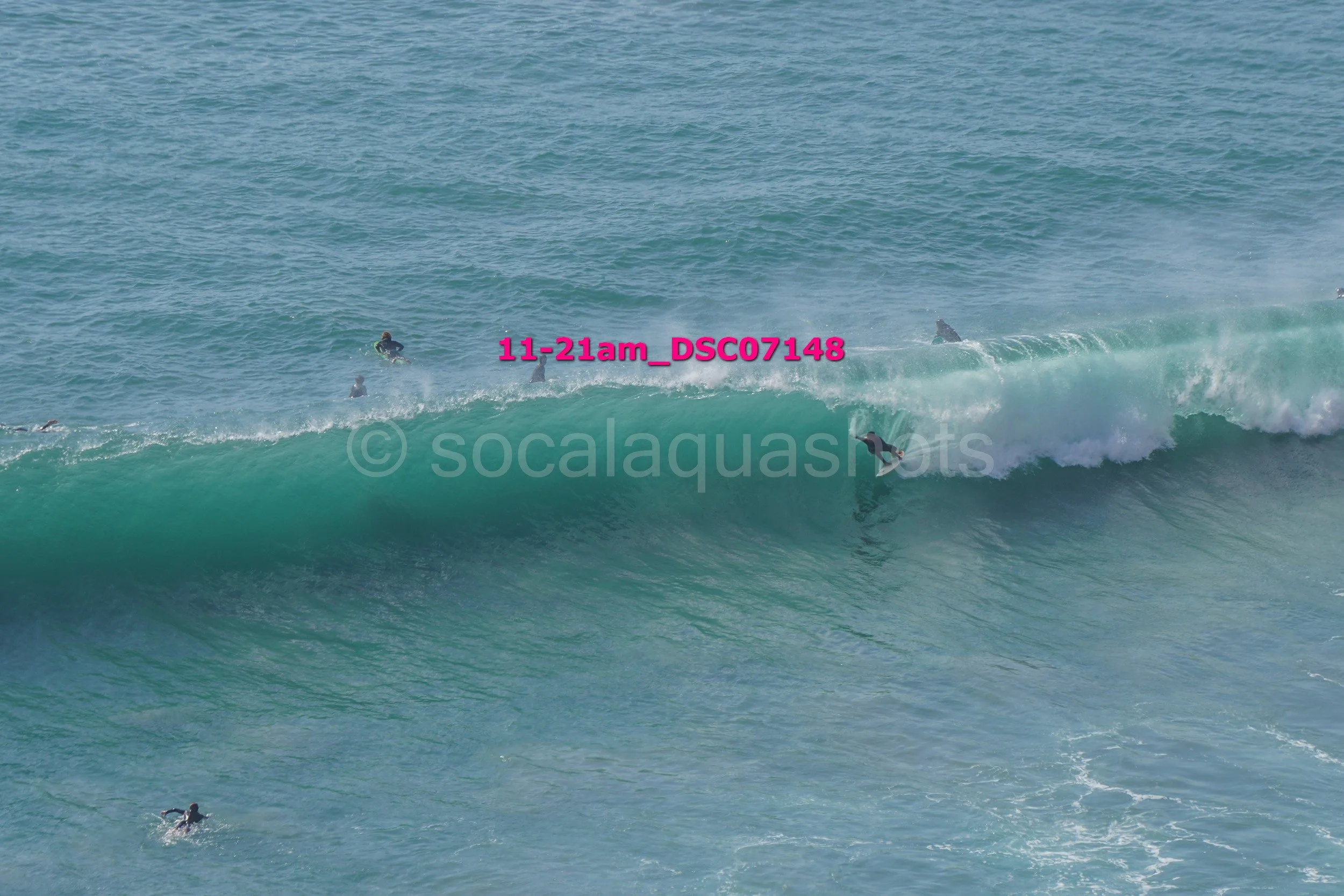 Surfers riding a wave in the ocean with some surfers in the water and others on the wave.