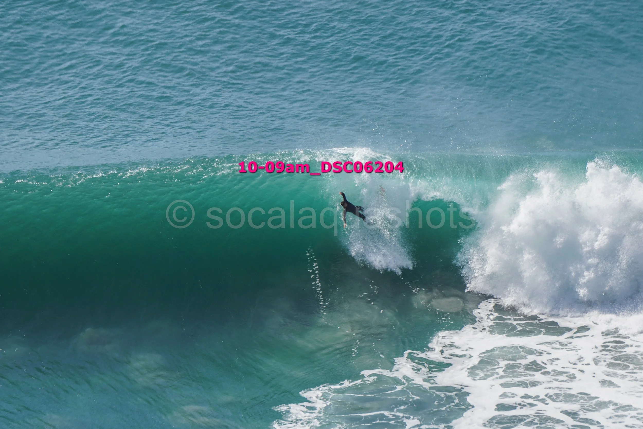 A surfer riding inside the wave with a crowd in the background