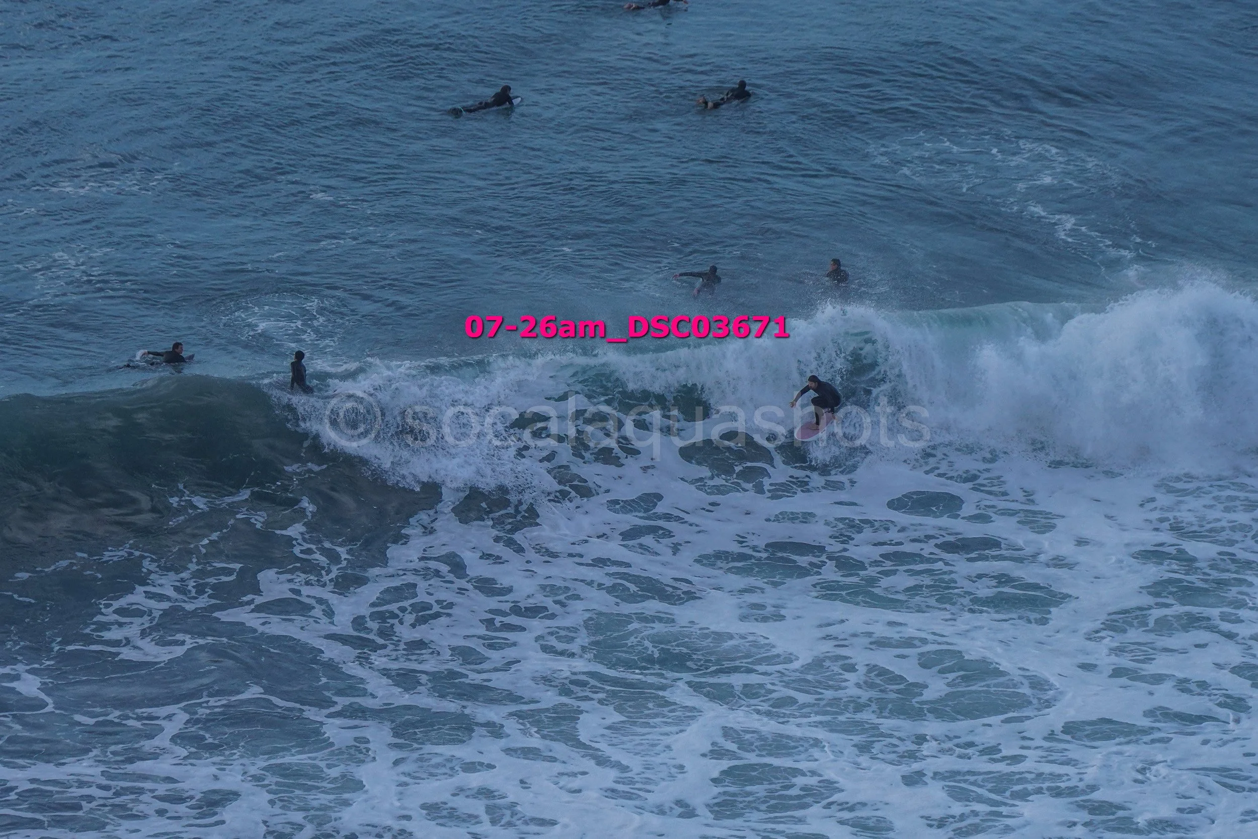 Multiple surfers riding and paddling on ocean waves.