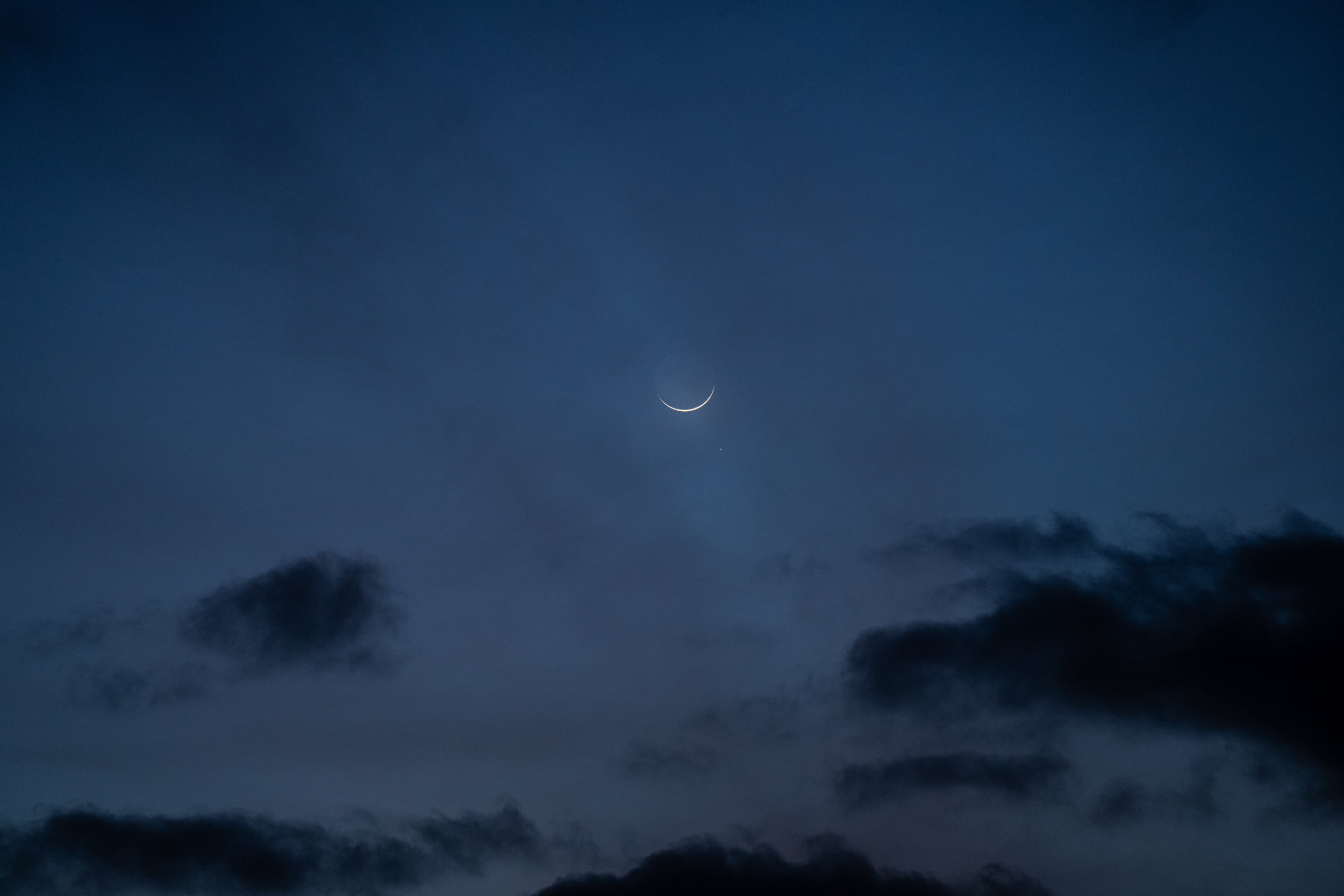 Night sky with a crescent moon and some dark clouds.