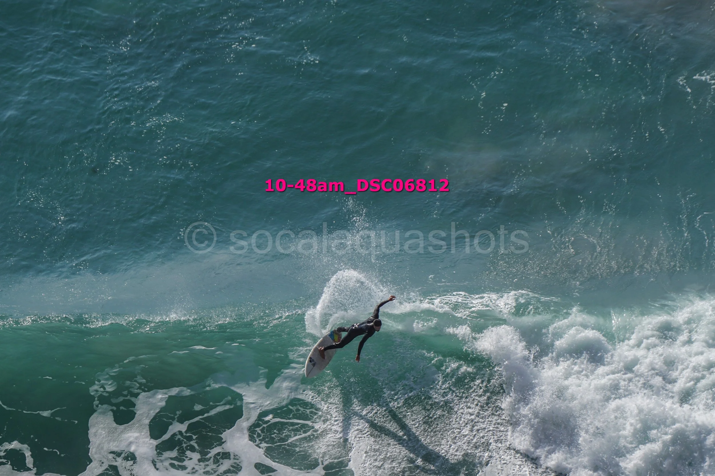 A surfer in black wetsuit riding a wave in the ocean during daytime.