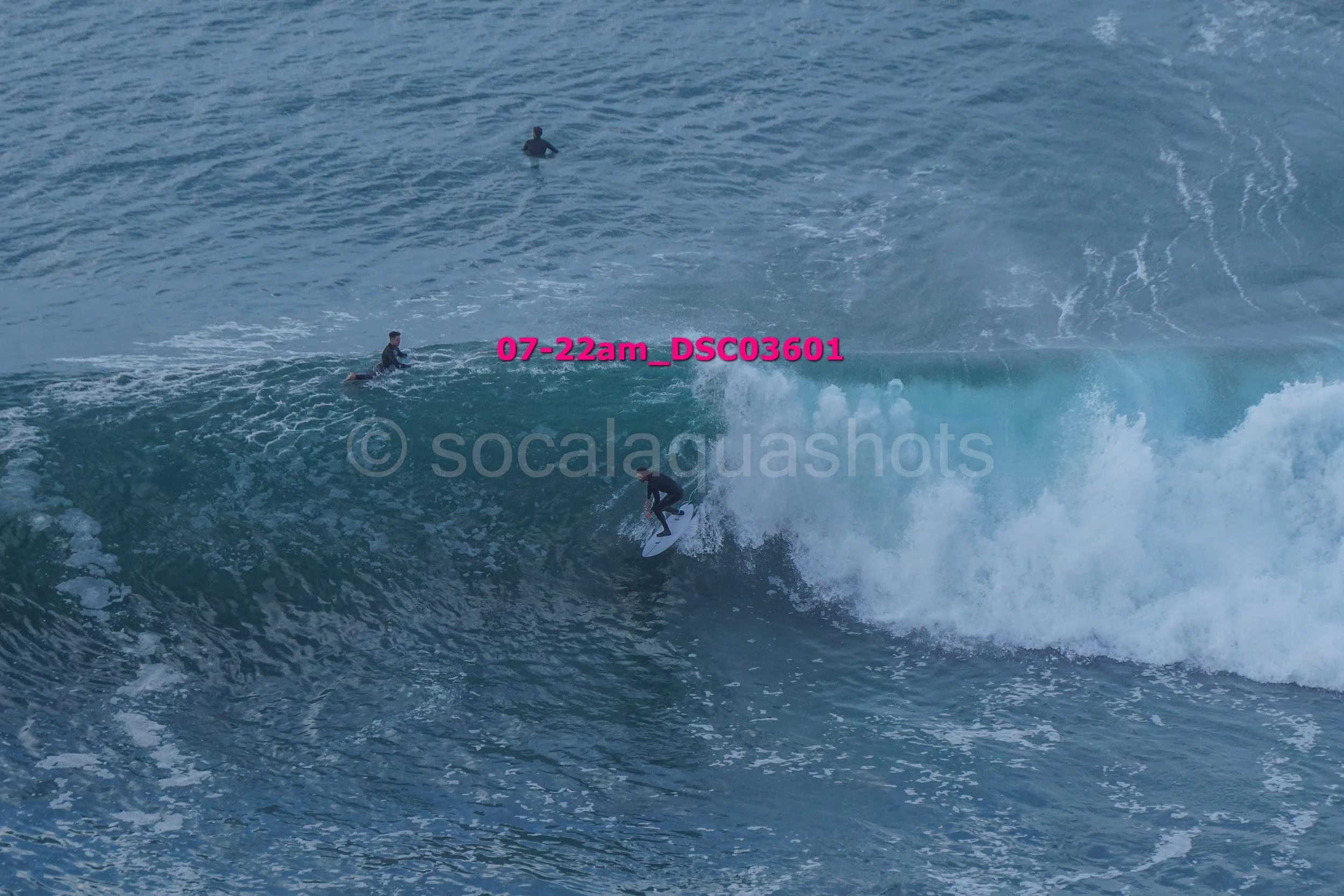 Surfer riding a large wave while three other surfers are in the water nearby.