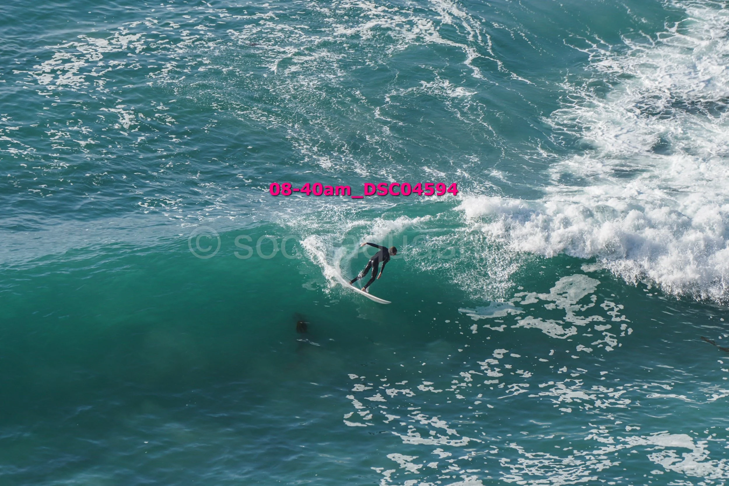 A surfer riding a wave in the ocean with visible white foam and water spray.
