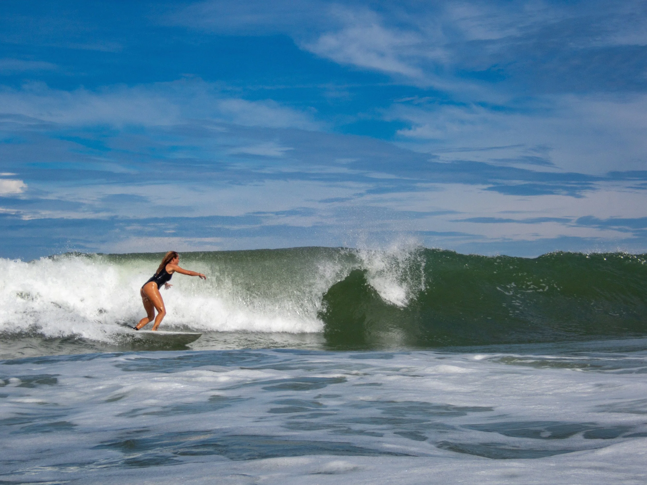 Surfer riding a wave in the ocean under a blue sky