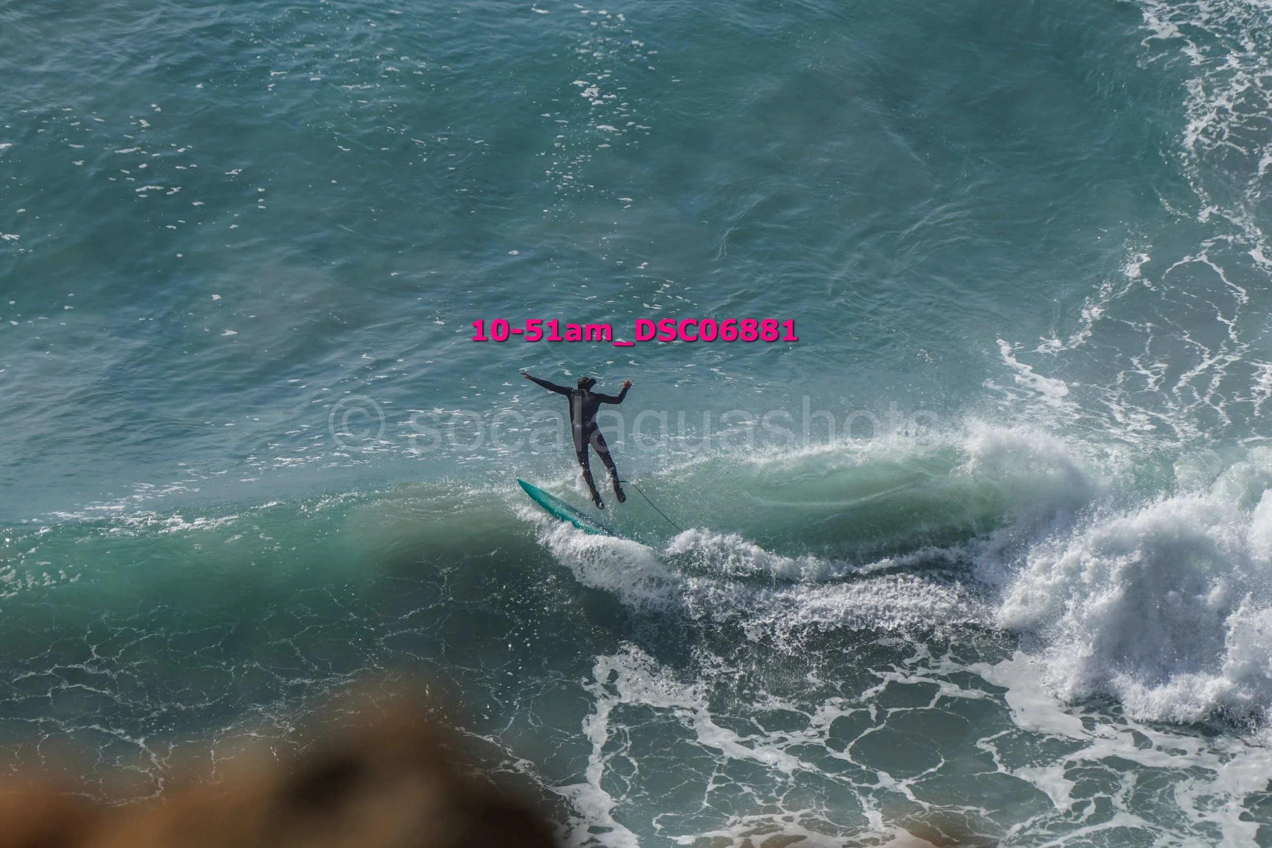 Surfer in a black wetsuit riding a wave at the beach.