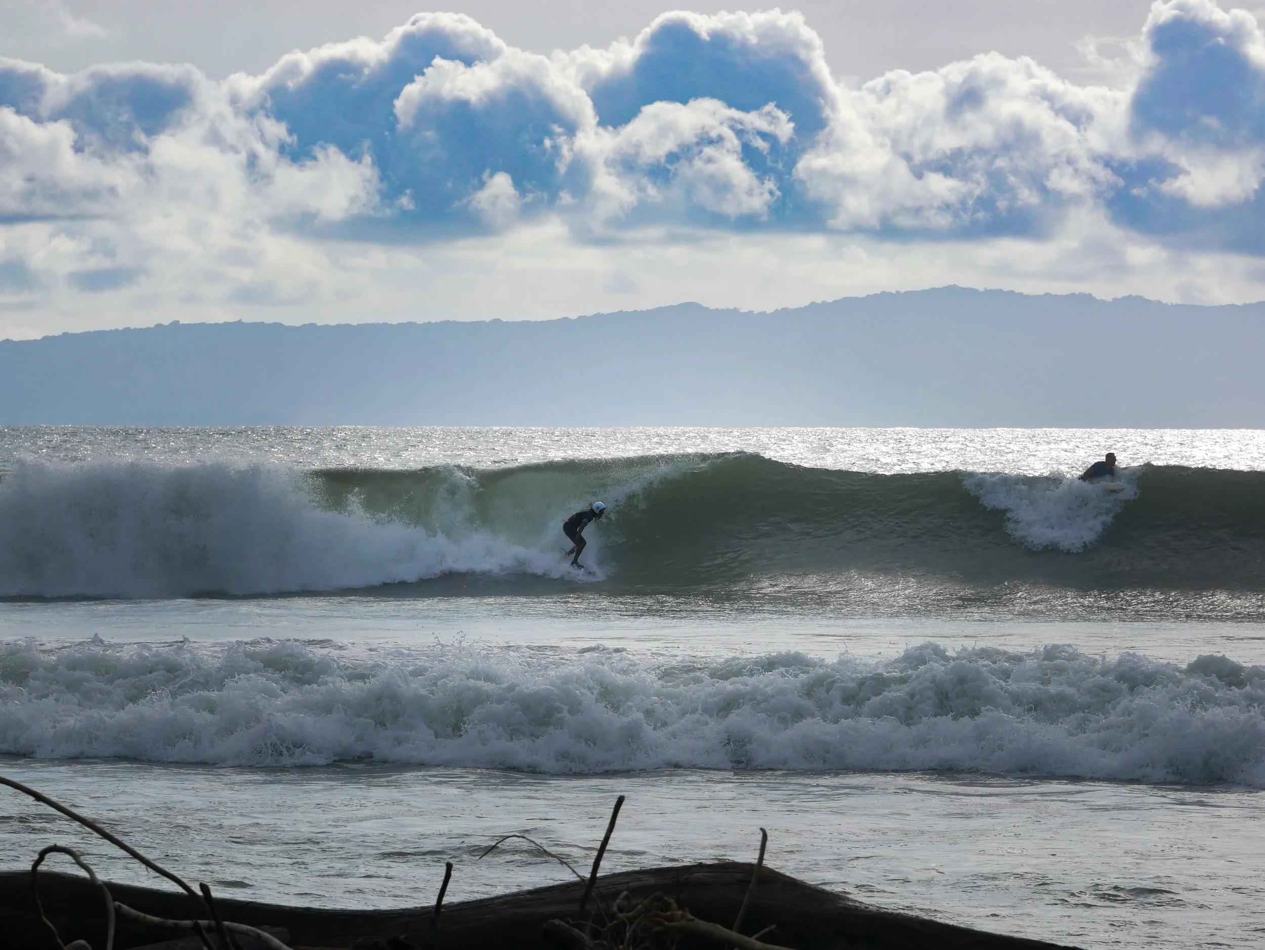 two surfers riding waves under cloudy sky