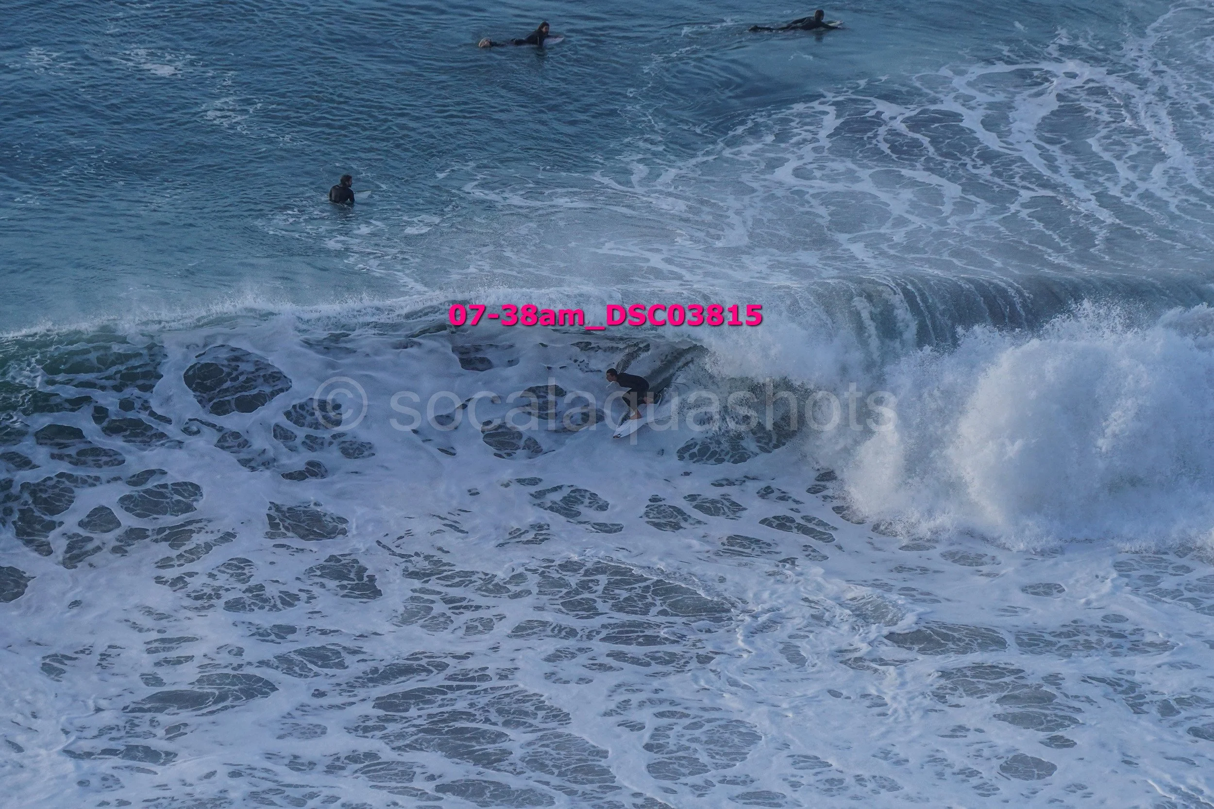 A surfer riding a wave with several people in the water nearby.