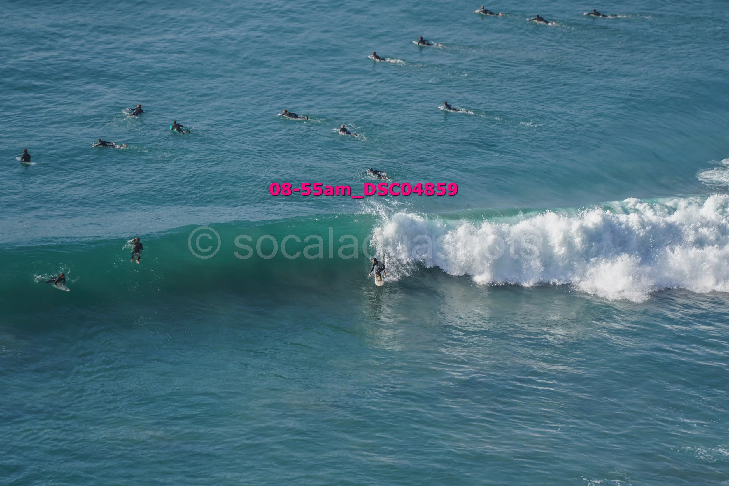 Surfer riding a wave with multiple surfers in the water around him.