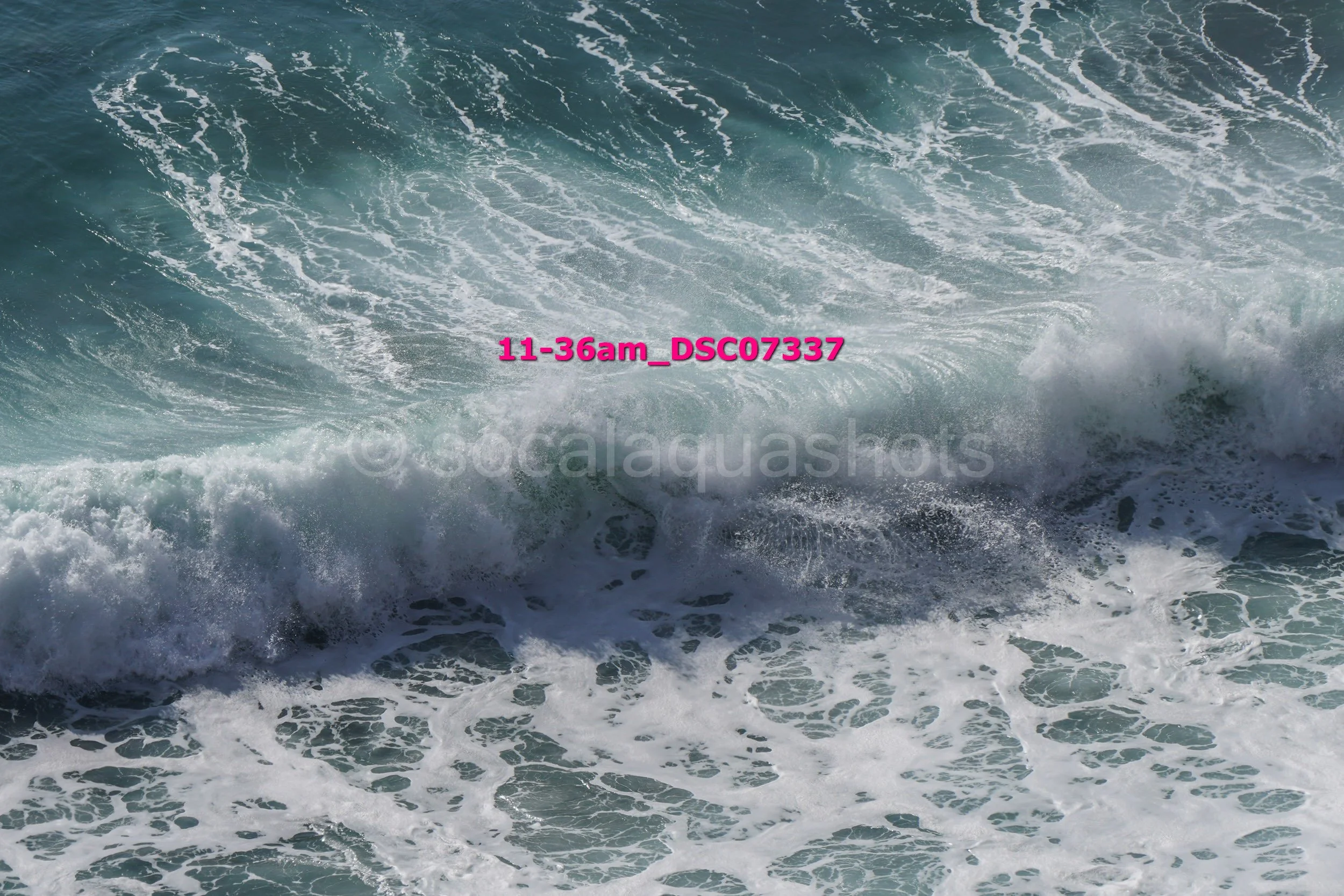 Ocean waves crashing with white foam and spray, viewed from above.