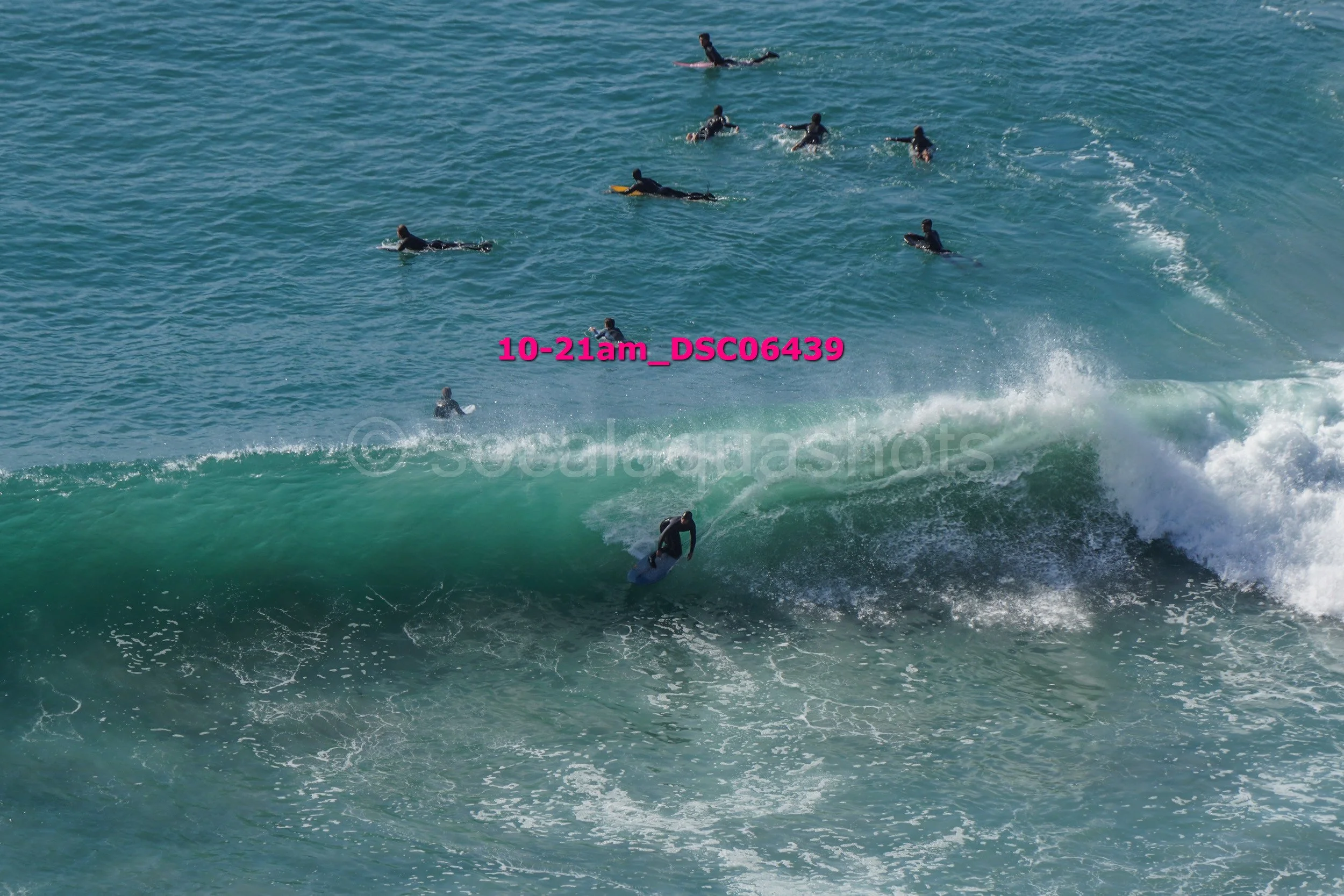 A surfer riding a wave with several surfers in the water in the background.