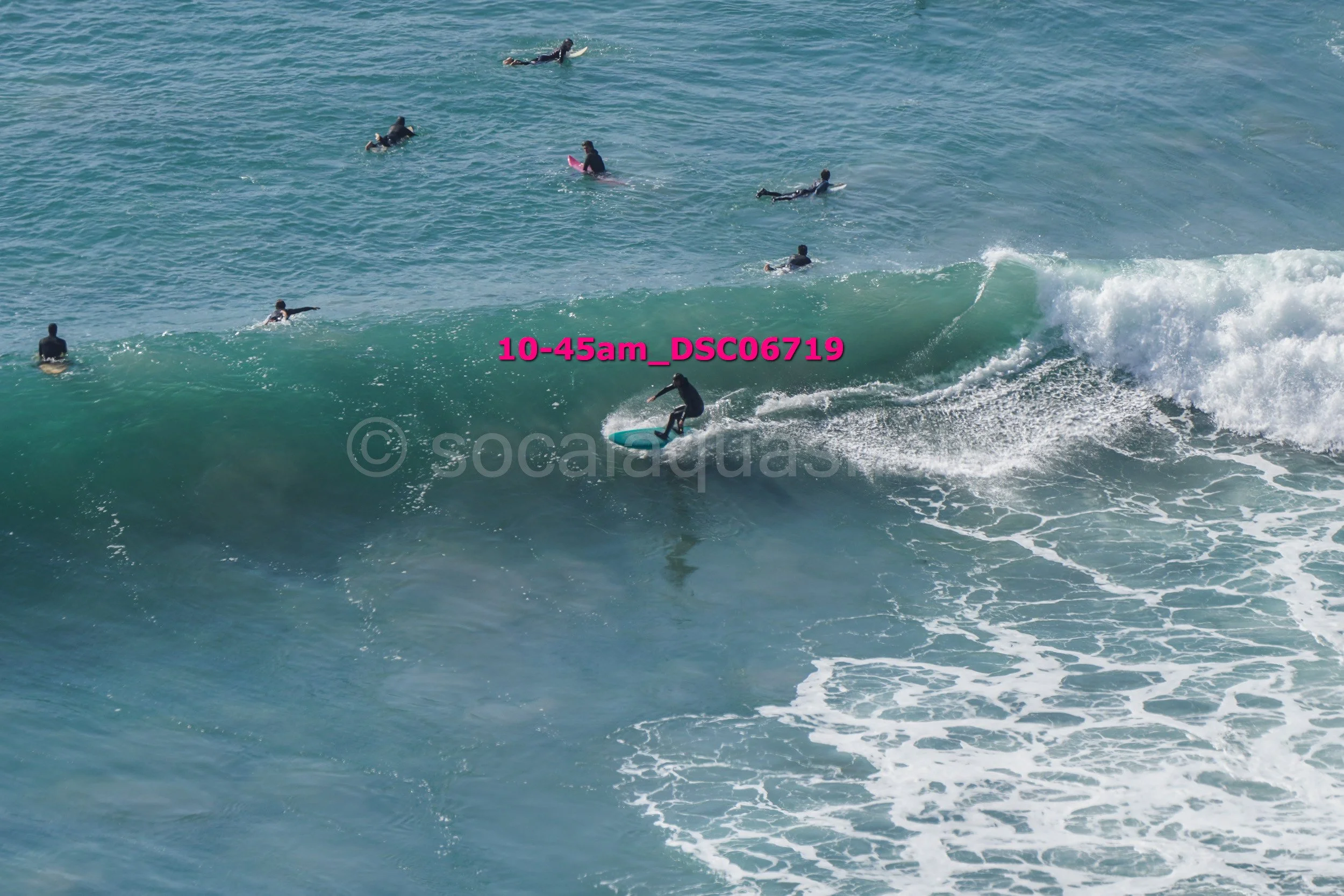 A person surfing on a wave with several other surfers in the water in the background.