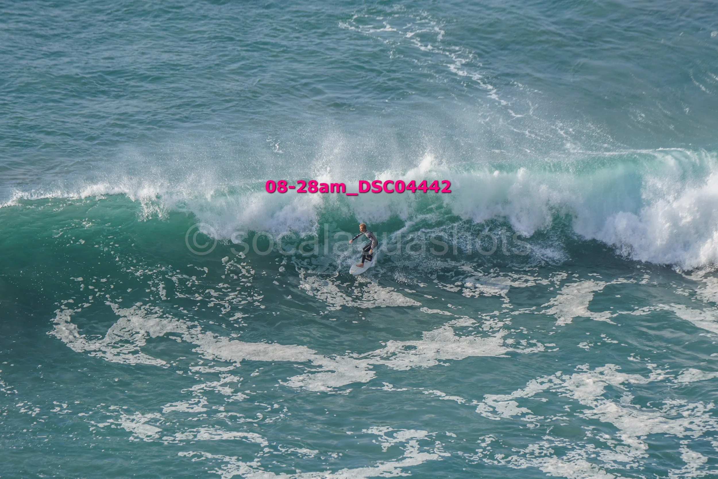 A person surfing on a large ocean wave with white foam and spray.