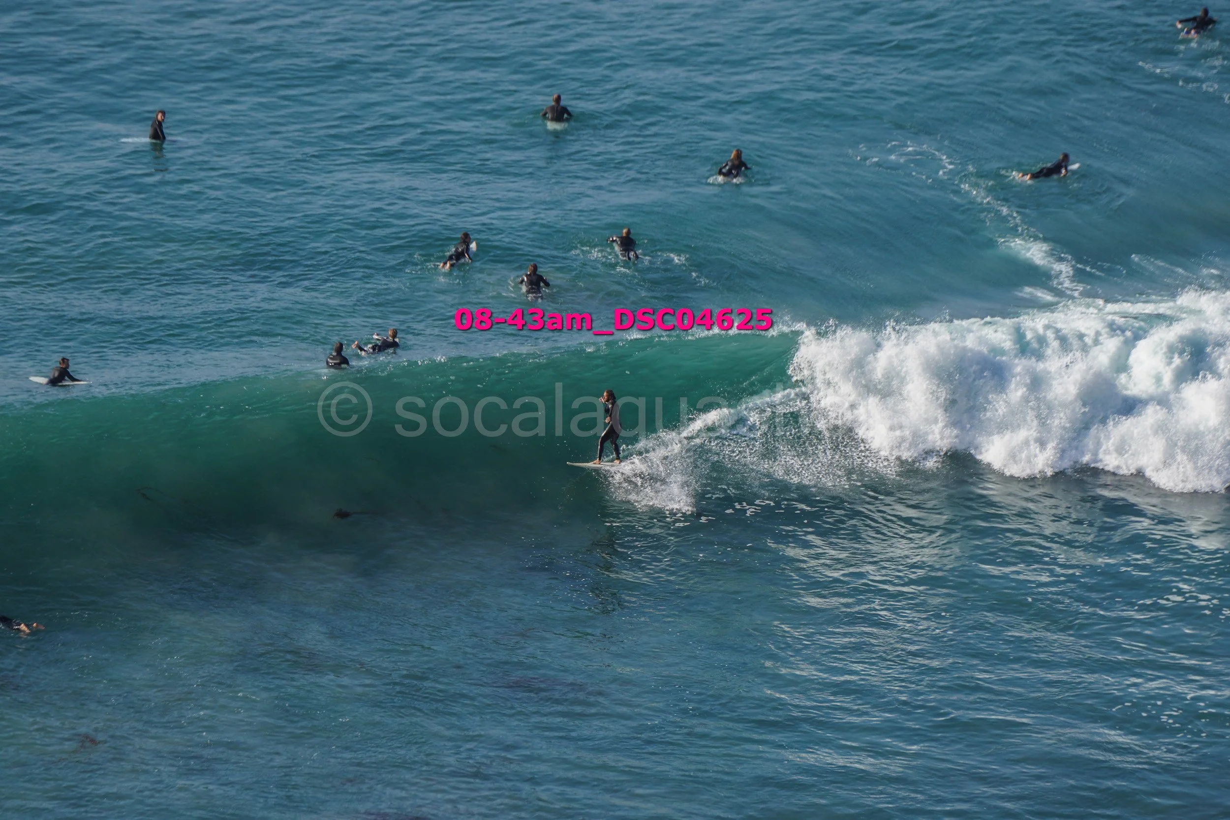 Surfer riding a wave with several people in the water watching or surfing in the background.