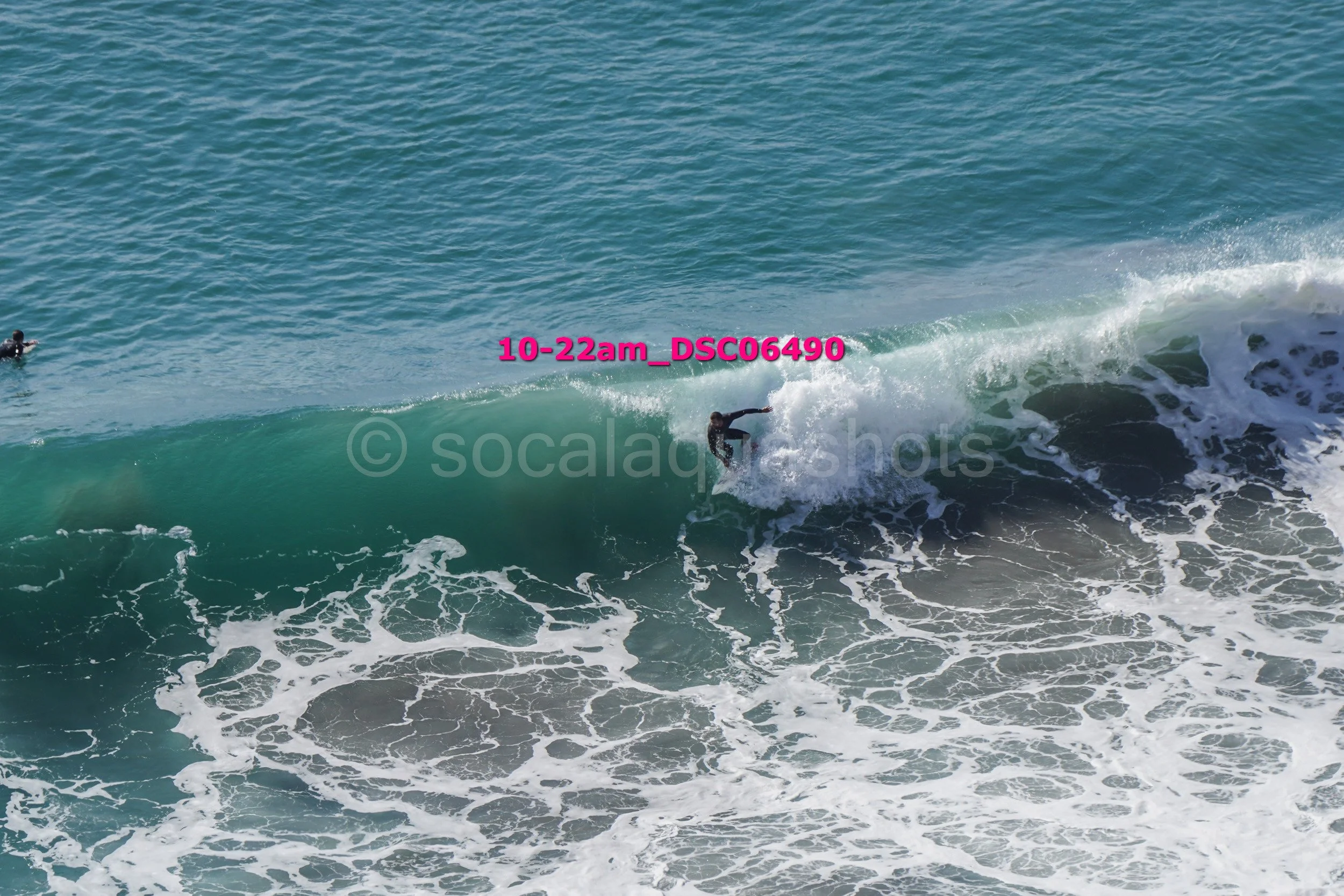 Surfer riding a wave in the ocean with another surfer in the background.