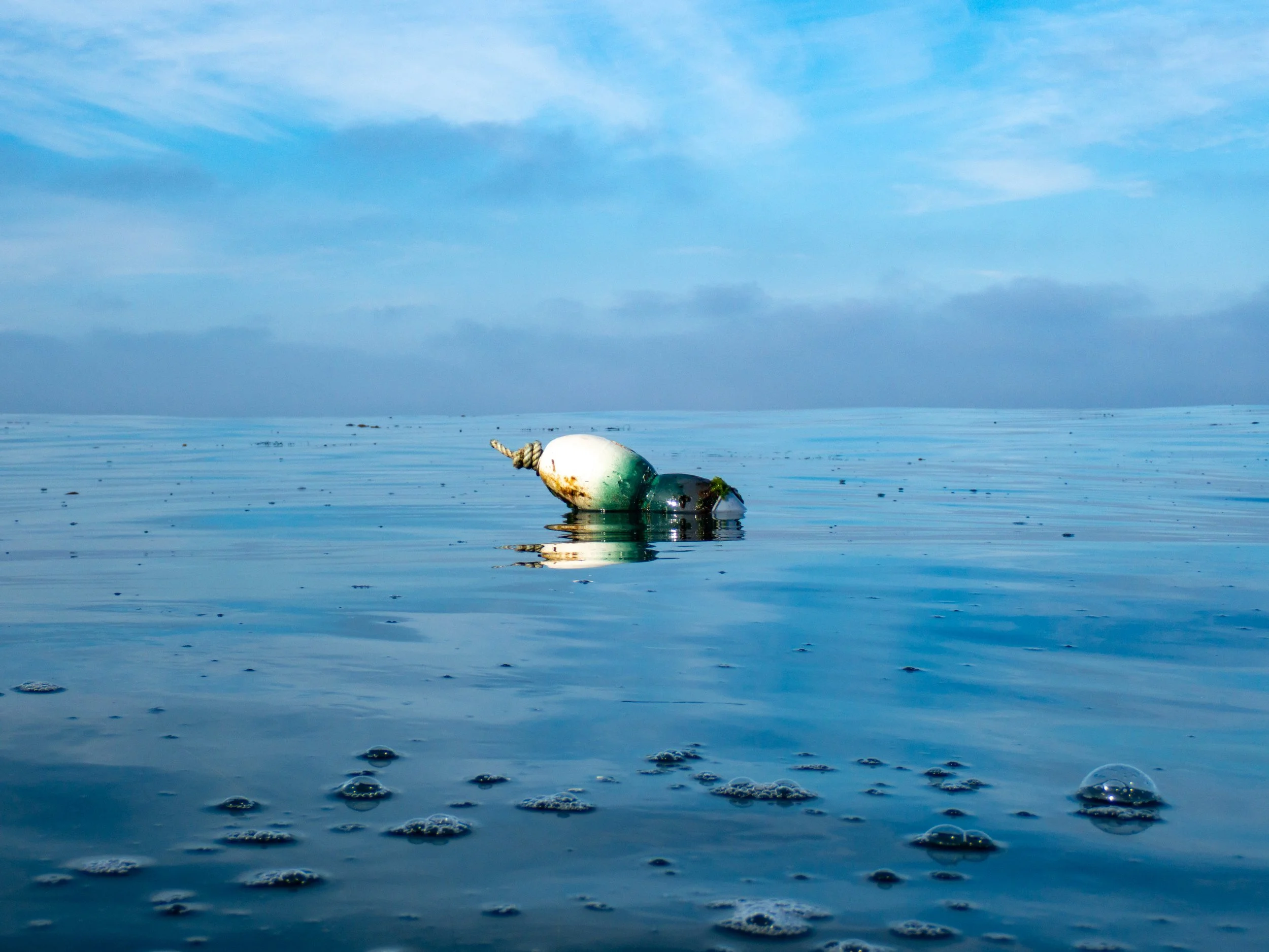 A floating buoy in the ocean with a cloudy sky in the background.