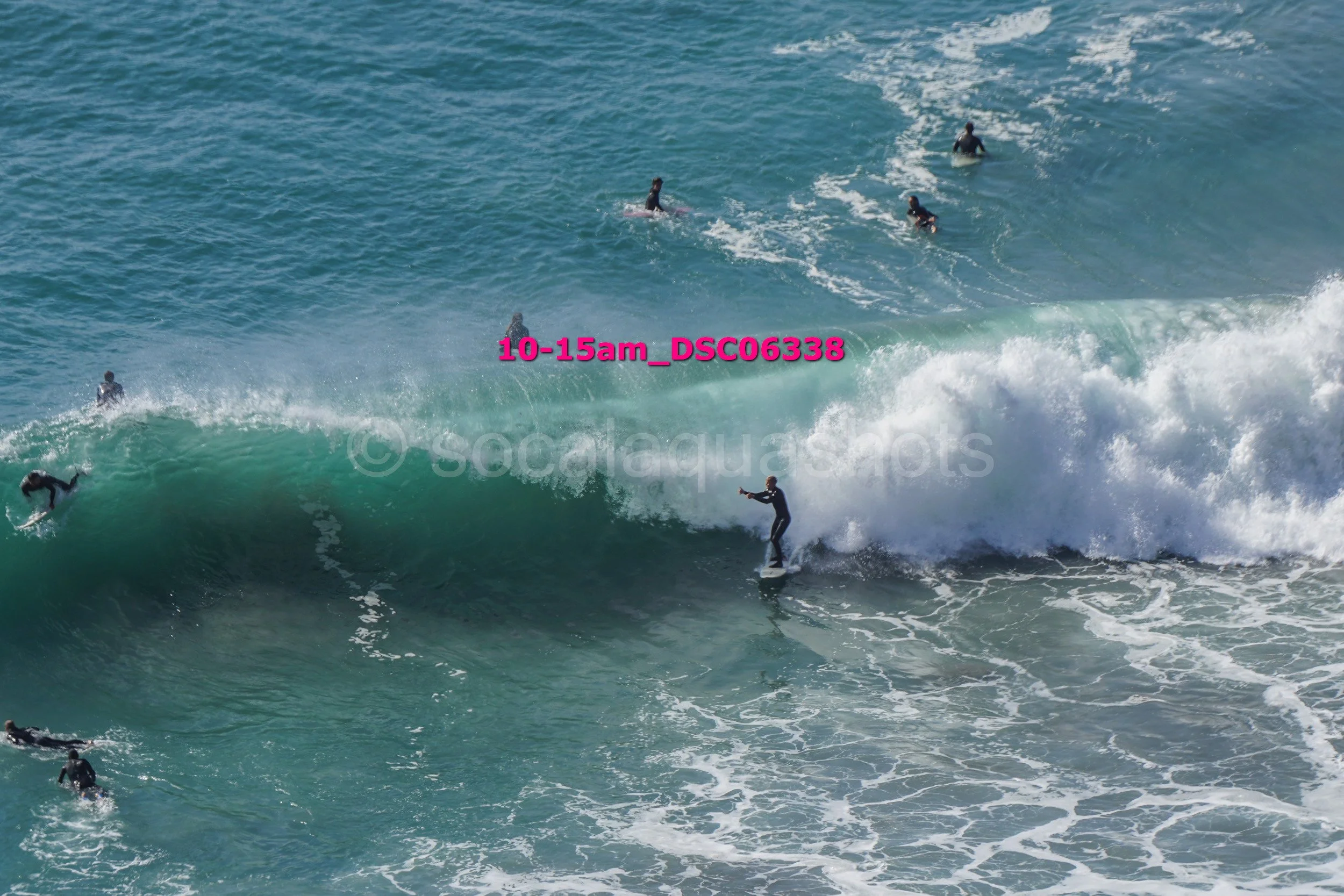 A surfer riding a wave while several other surfers are in the water around him in the ocean.