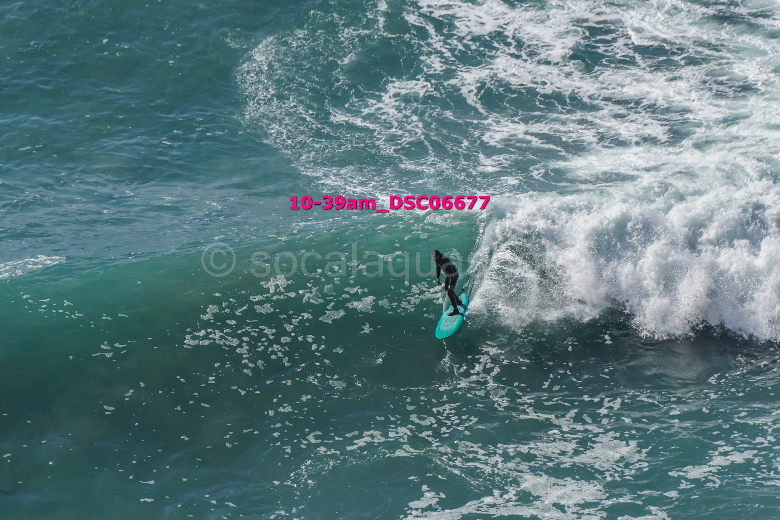 A person surfing on a blue surfboard in the ocean waves.
