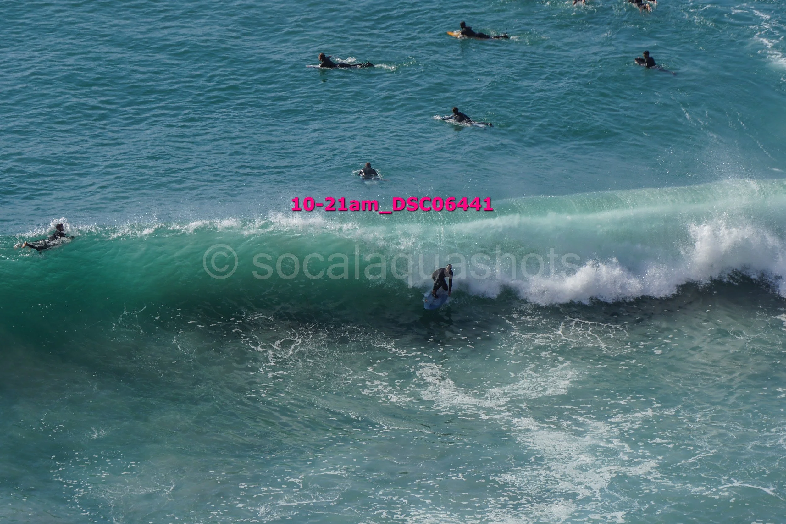 Surfers riding and paddling on large ocean waves.