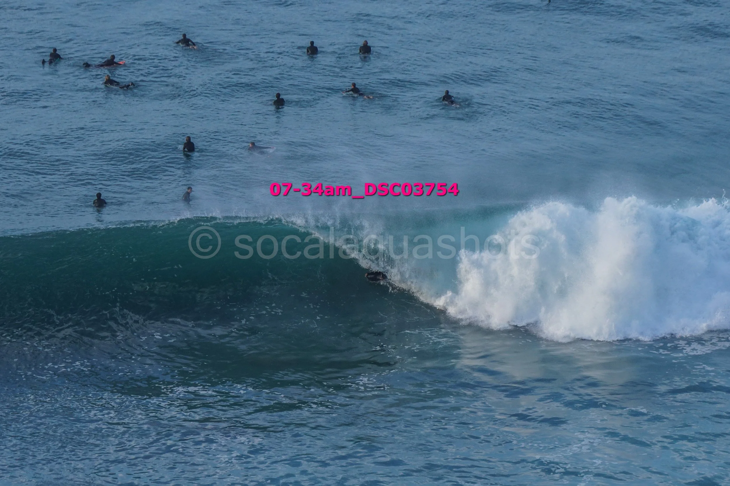 Surfer riding a wave with several surfers in the water nearby.