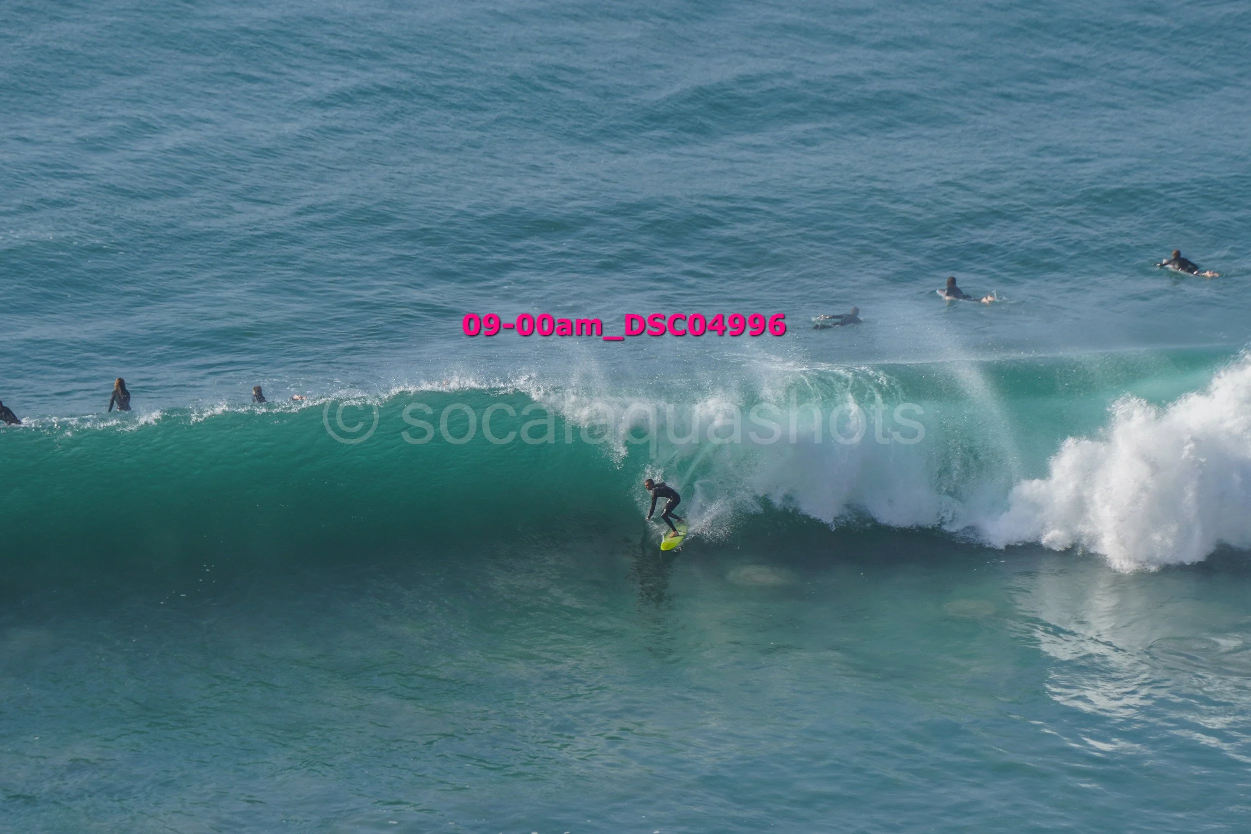 A surfer riding a wave with several surfers in the water in the background.