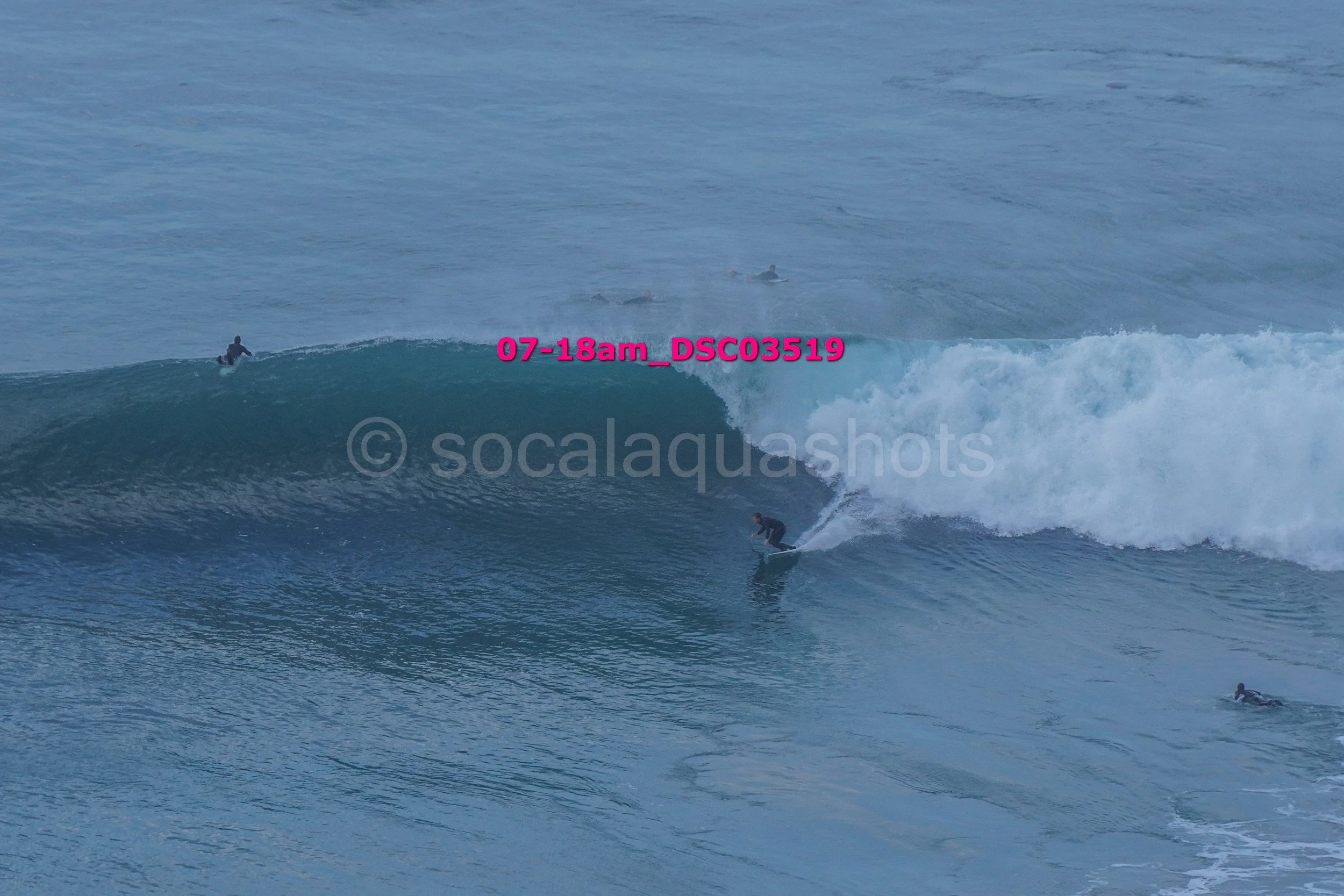 Surfer riding a wave with several surfers in the water in the background.
