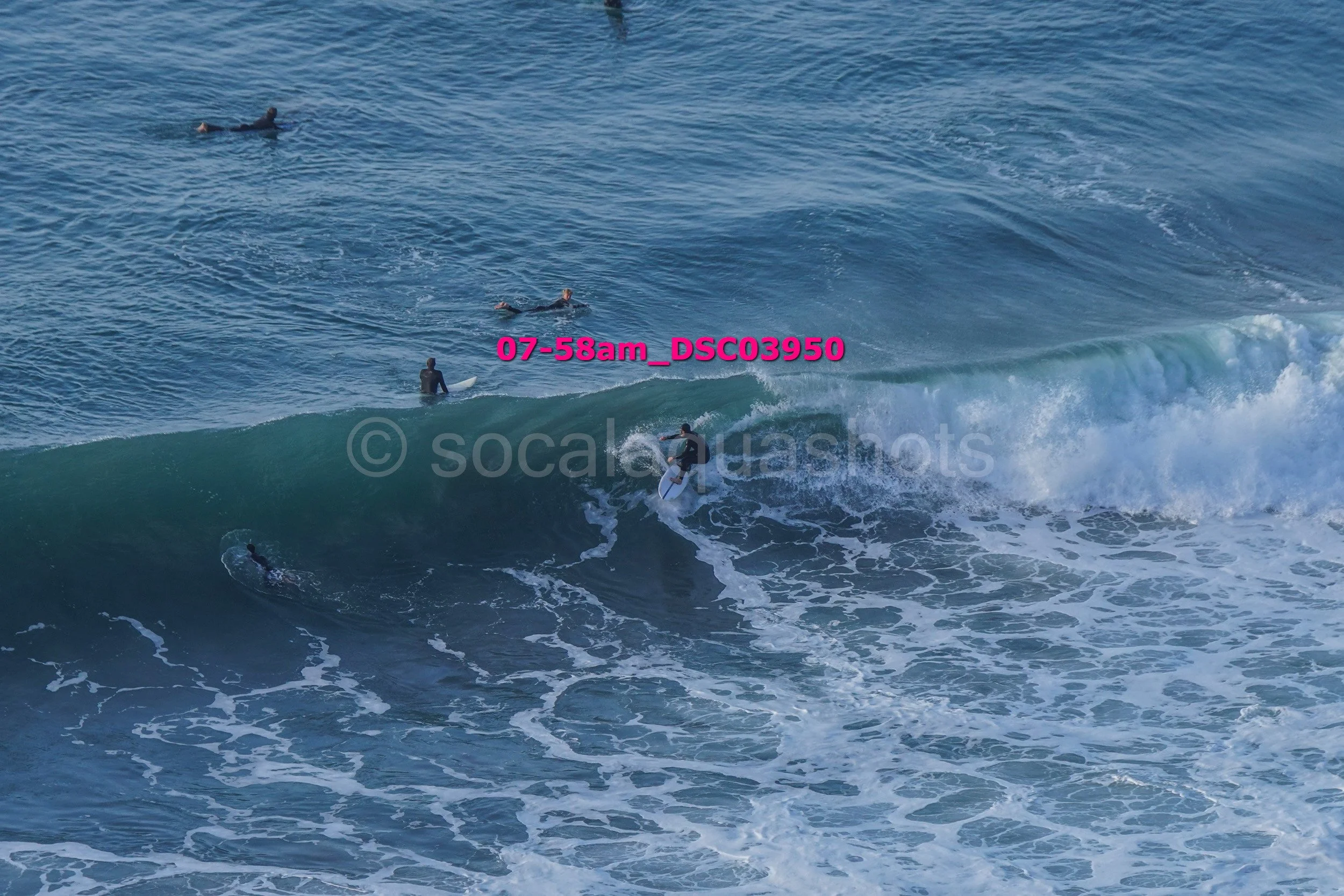 Surfer riding a wave with several surfers in the water nearby.