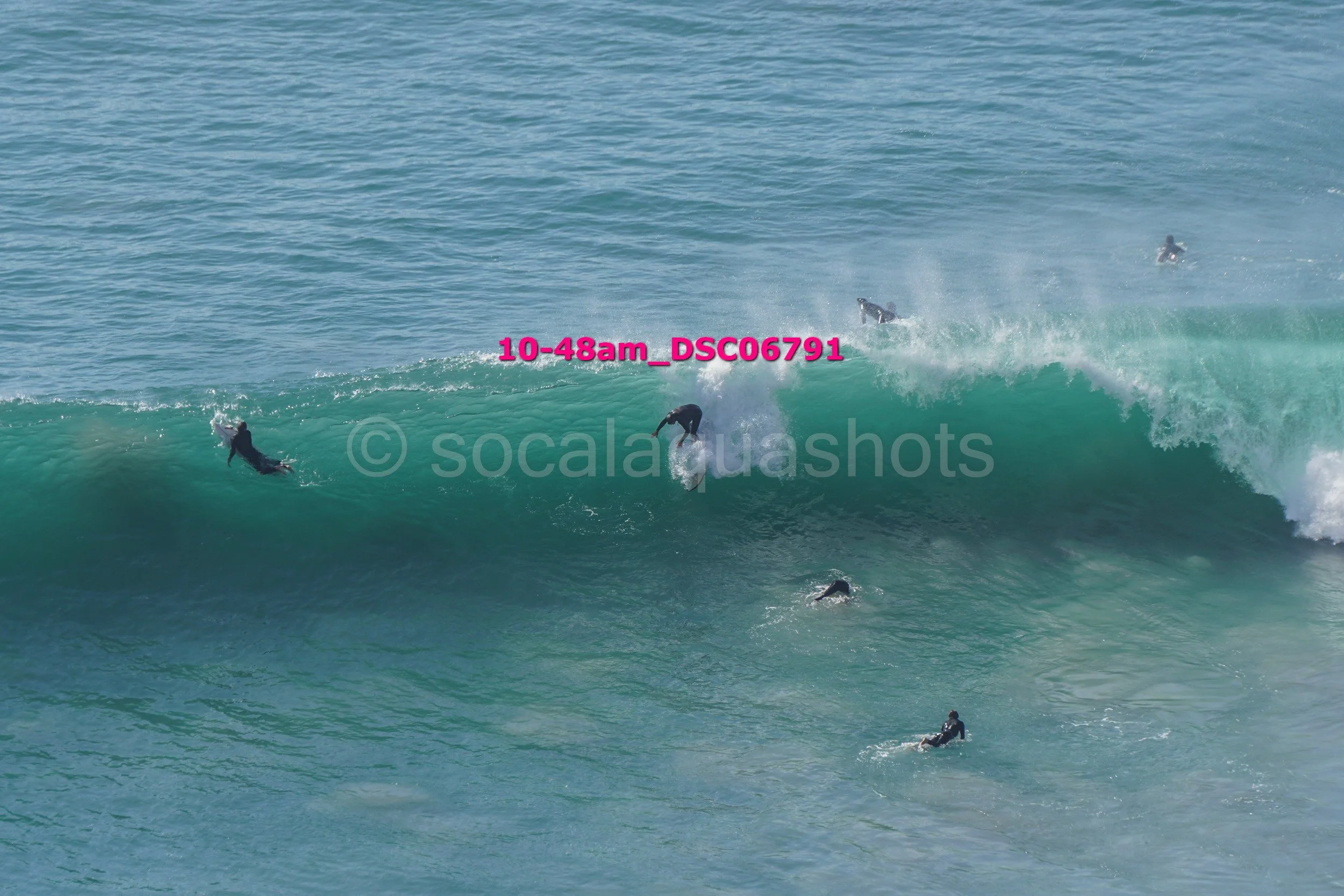 Multiple surfers riding and swimming in large ocean waves.