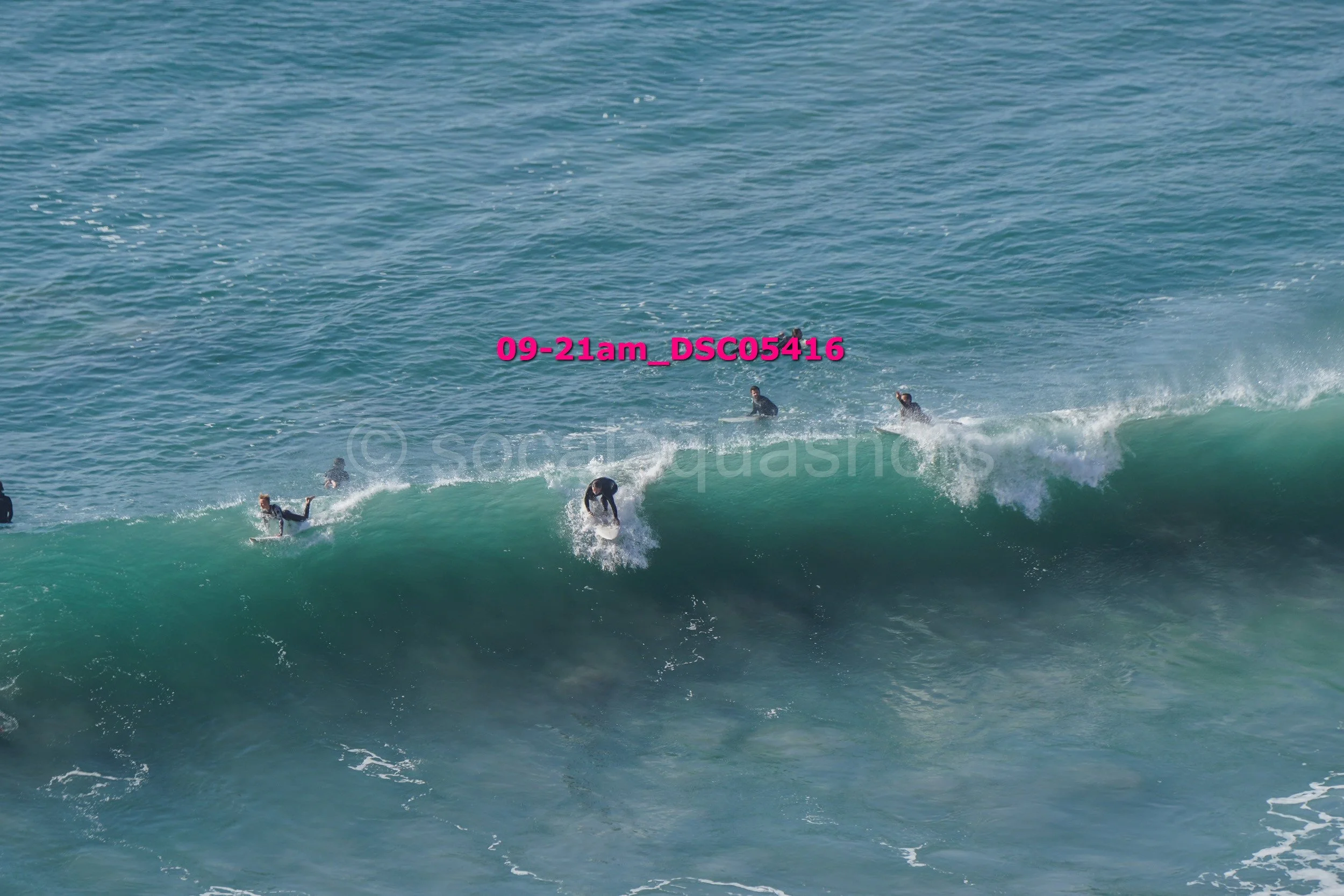 People surfing on ocean waves with a clear blue sky.