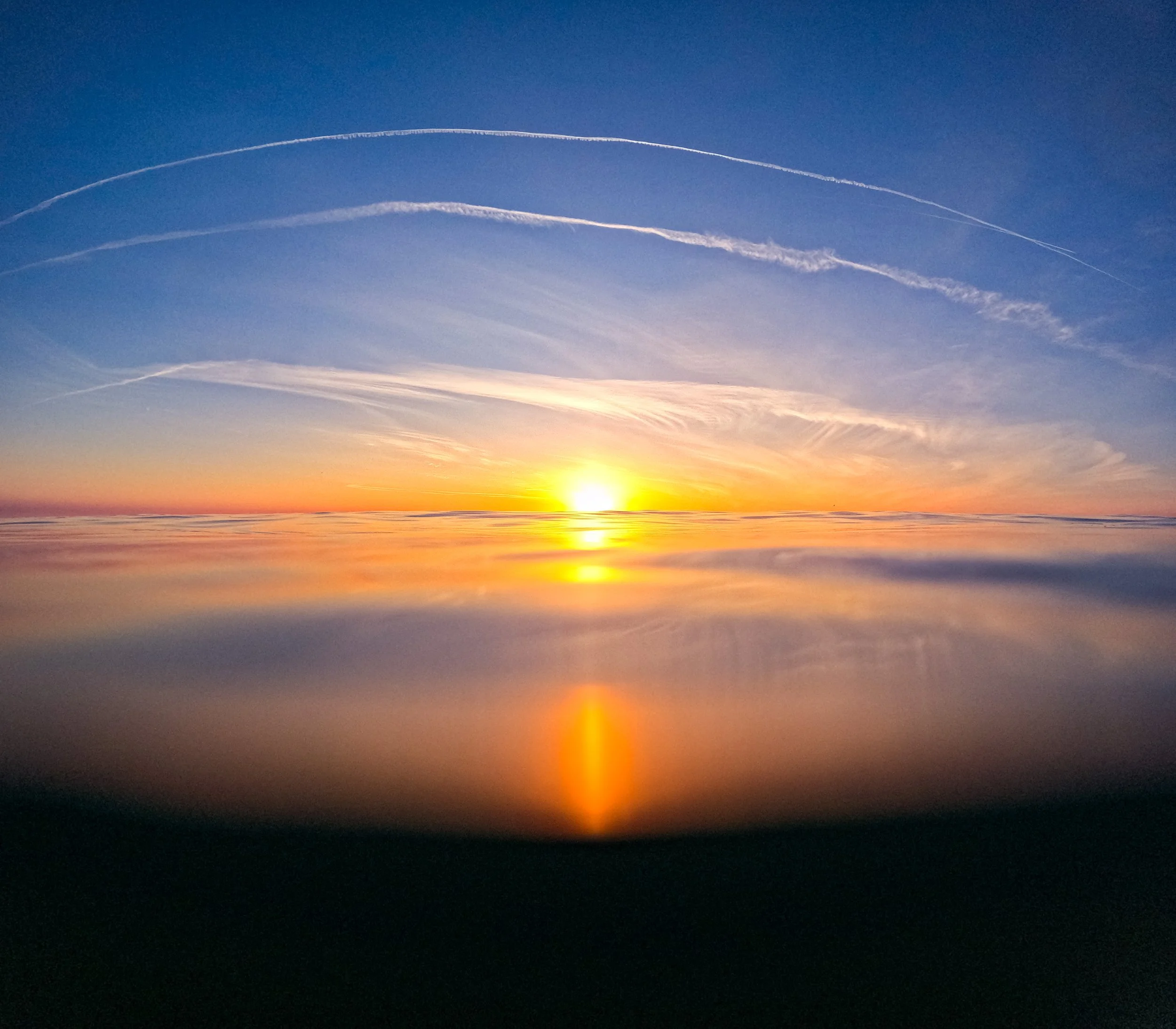 A vibrant sunset over a calm ocean with colorful sky and reflected sunlight on the water.